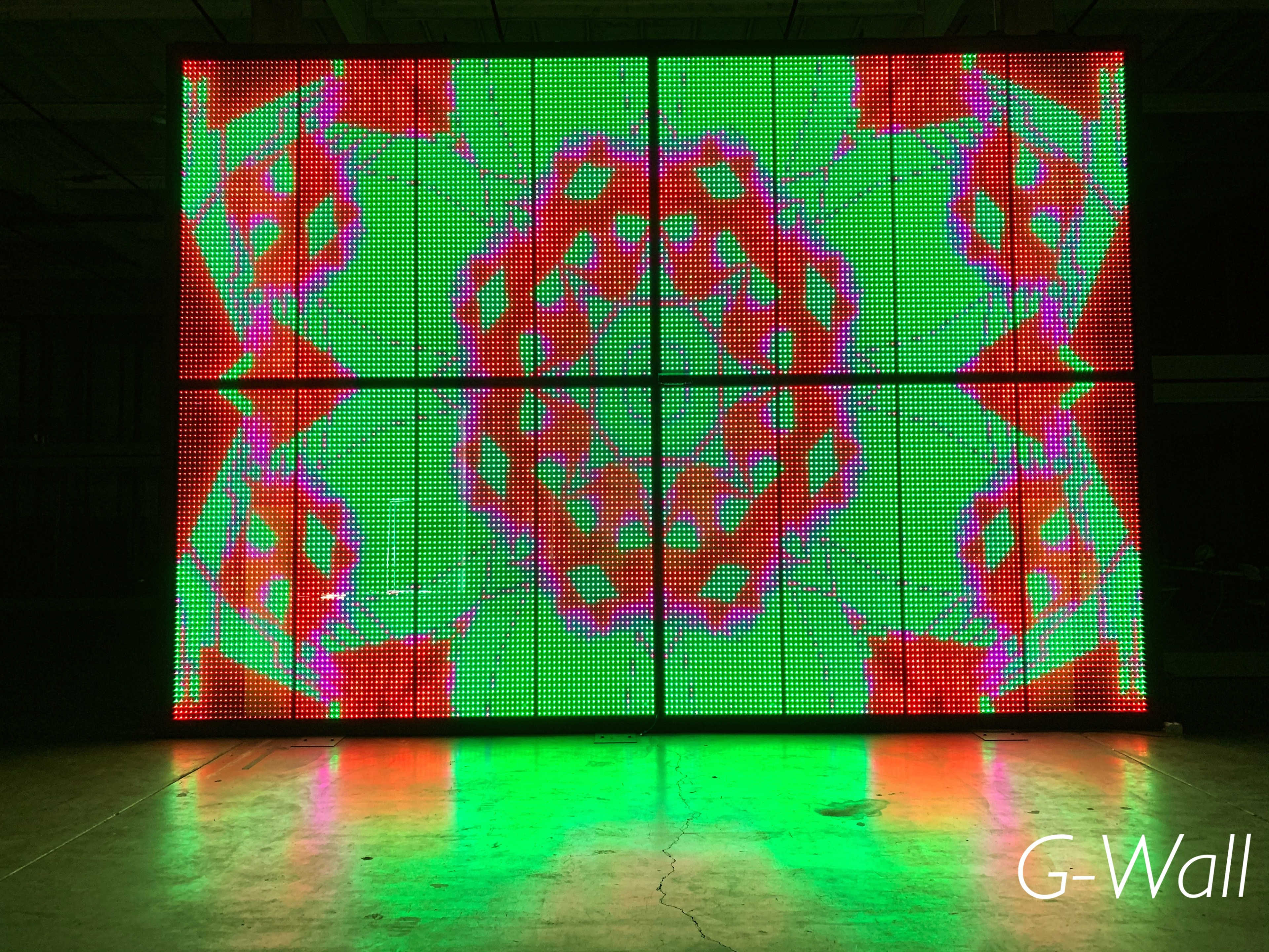 A large LED screen displays a colorful geometric pattern in green, red, and orange.