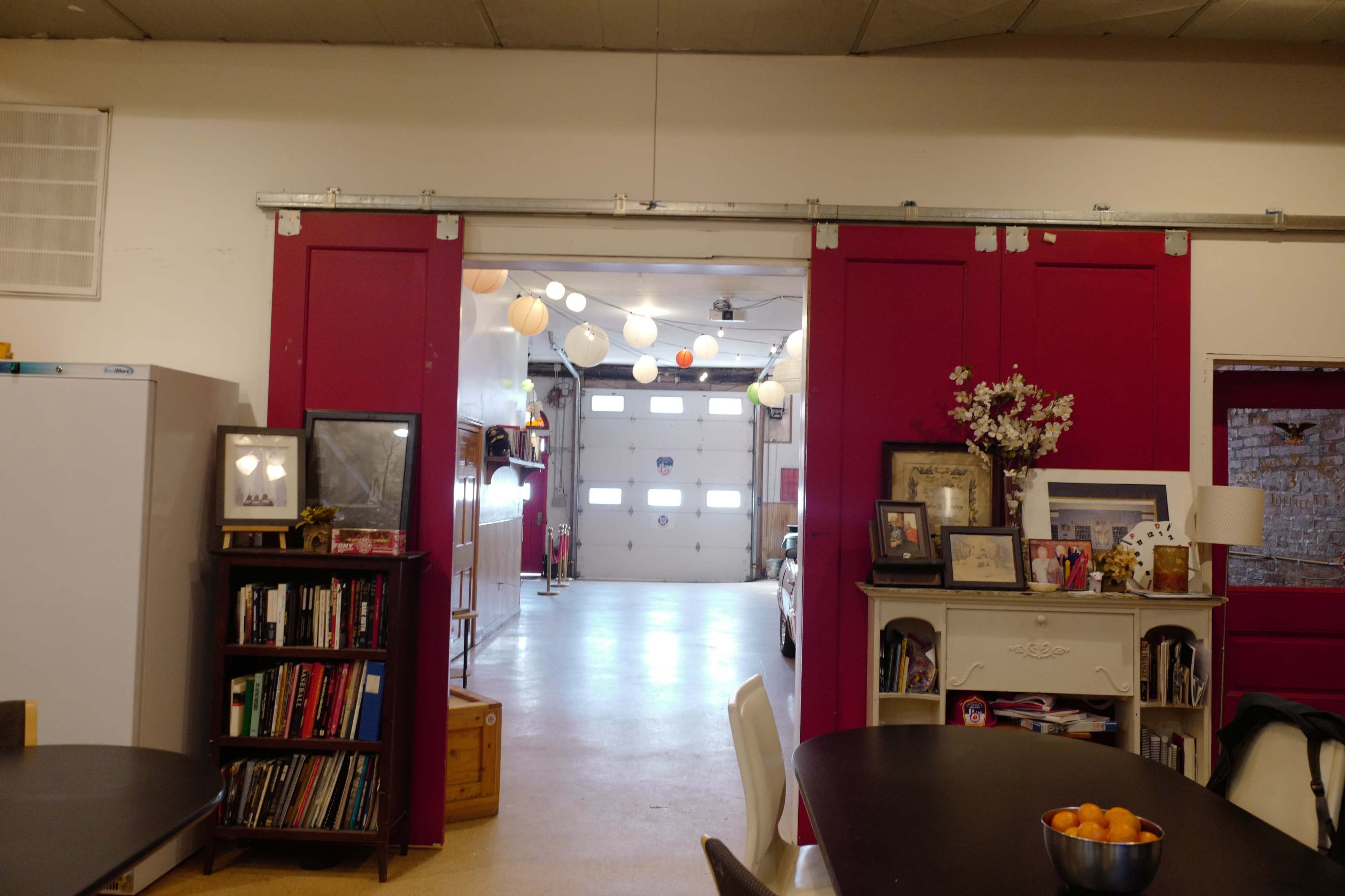 The image shows an interior view of a garage space with pink walls, shelving units, and decorative hanging lanterns.