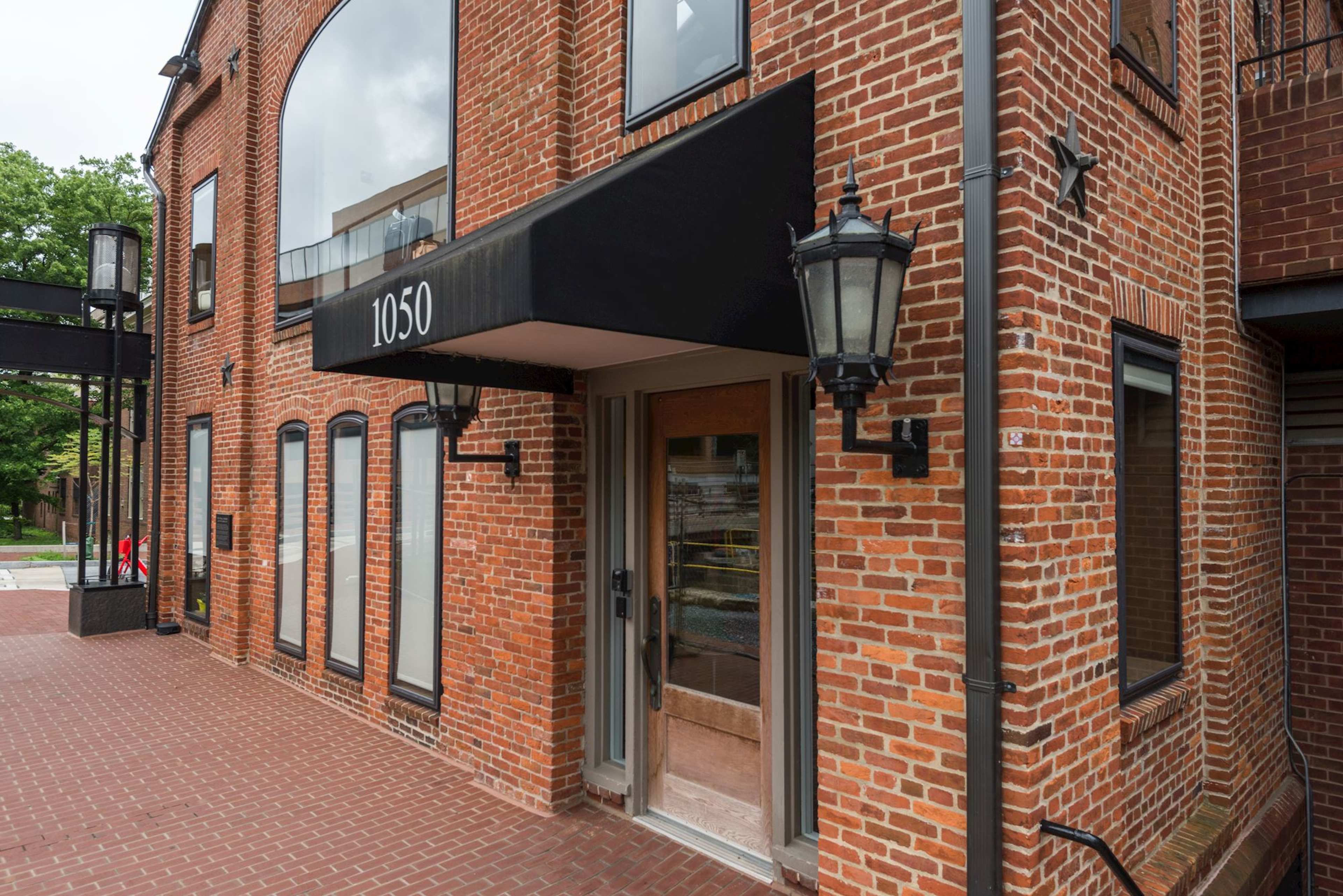 The image shows a brick building with a dark awning over the entrance, marked with the number 1050.