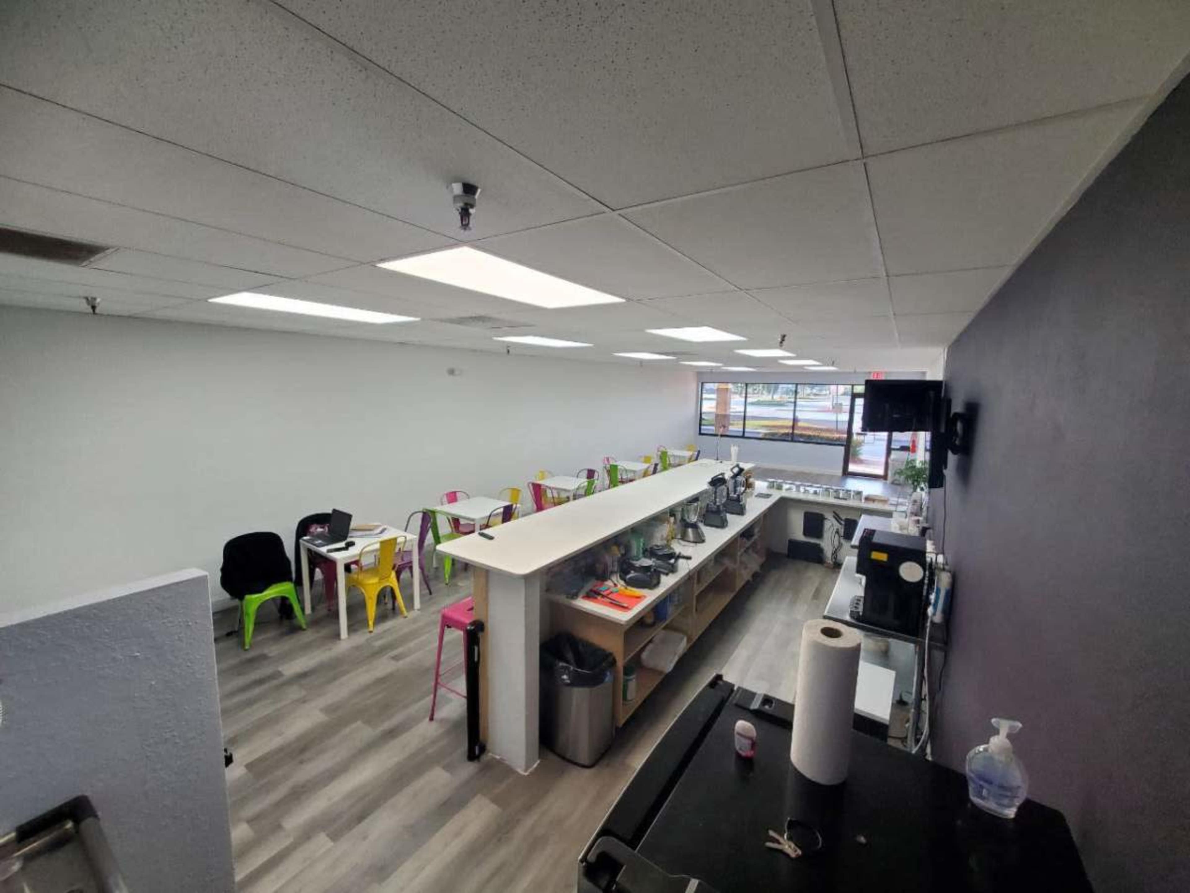 A spacious café interior with a counter, seating area, and large windows letting in natural light.