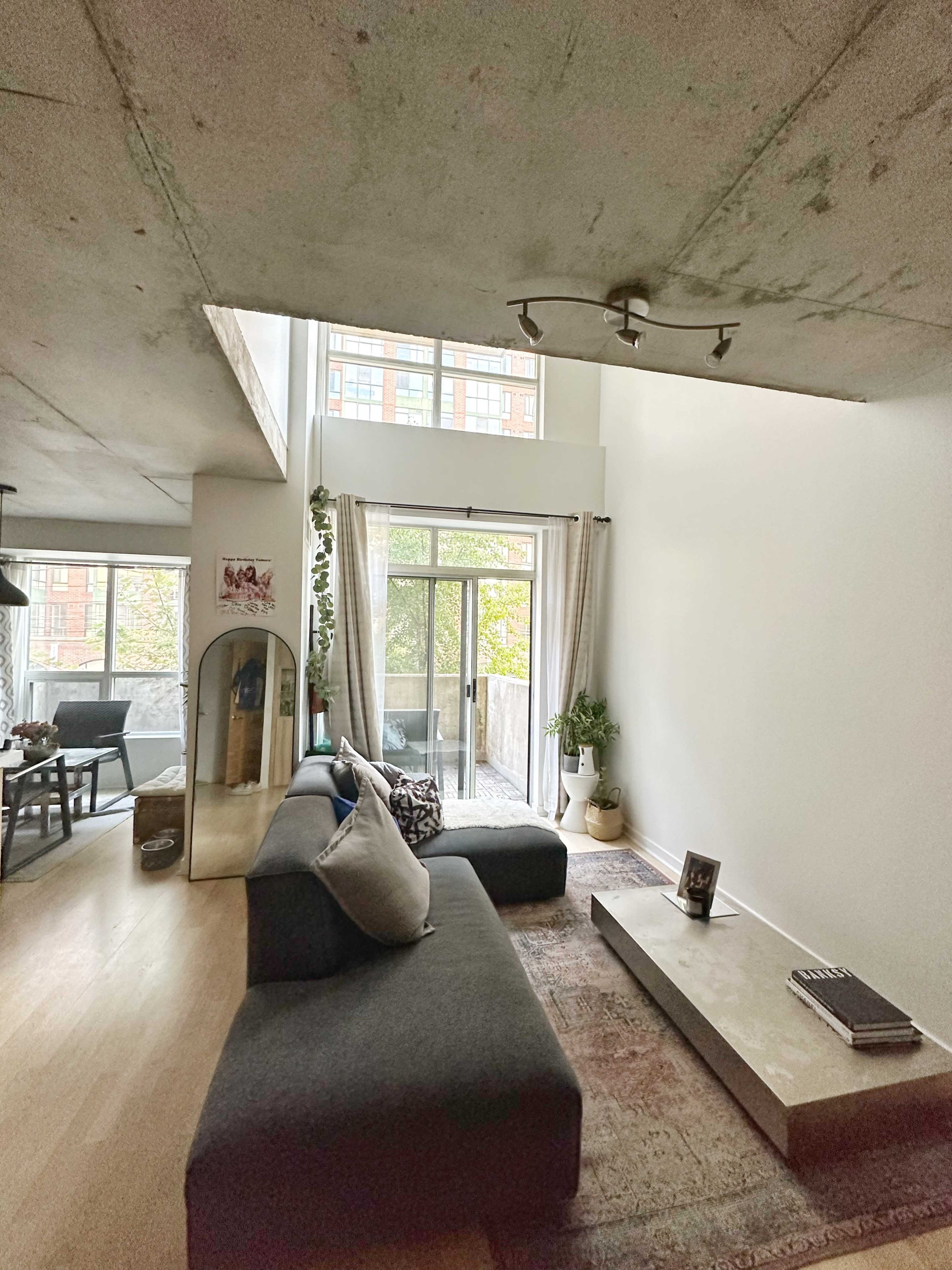 A modern living room featuring a gray sectional sofa, a low coffee table, and large windows allowing natural light to enter the space.
