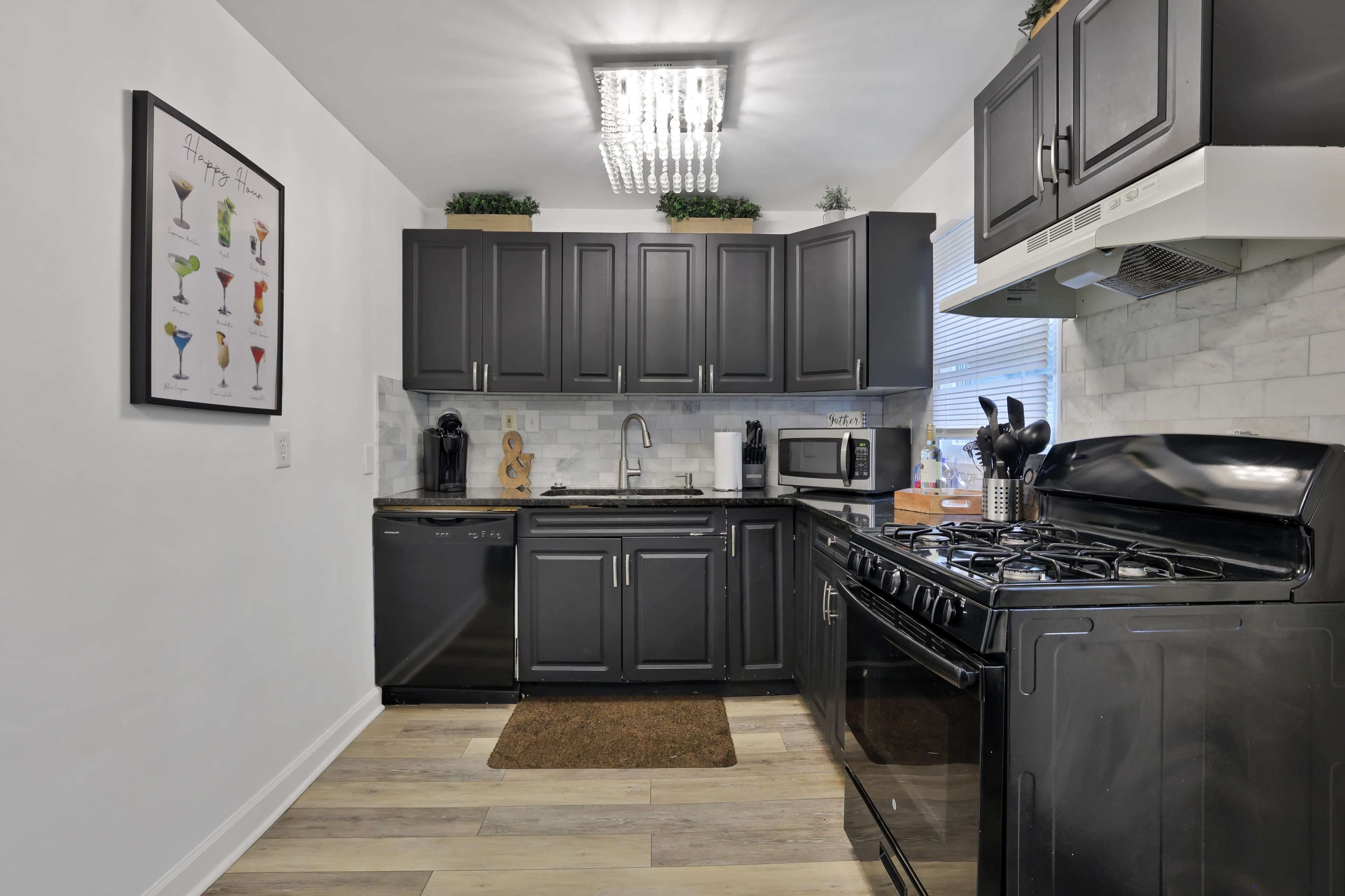 A modern kitchen with dark cabinetry, a gas stove, and stainless steel appliances.
