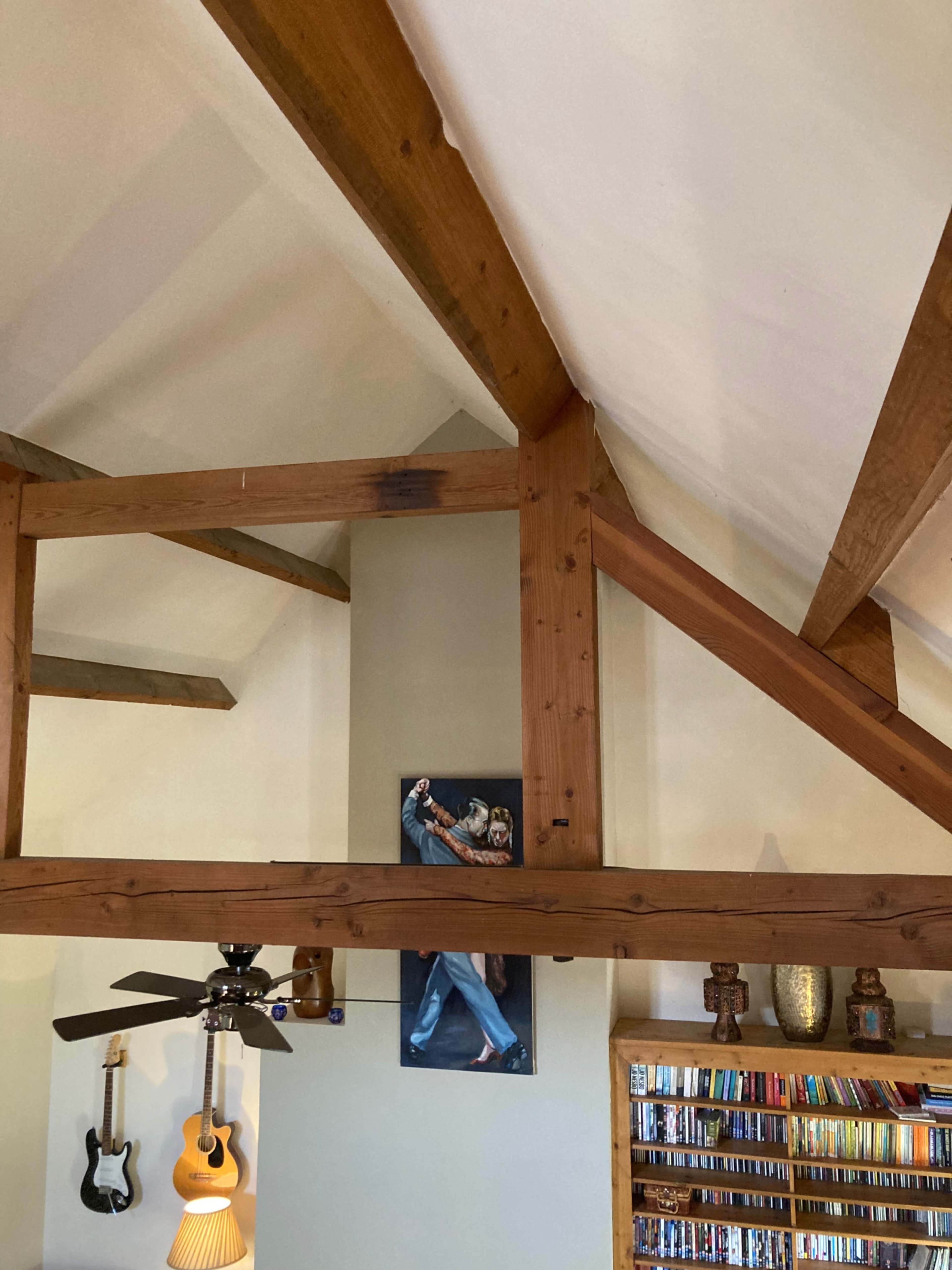 A wooden-beamed ceiling with a painting of a dancing couple on the wall and shelves of CDs in the corner.