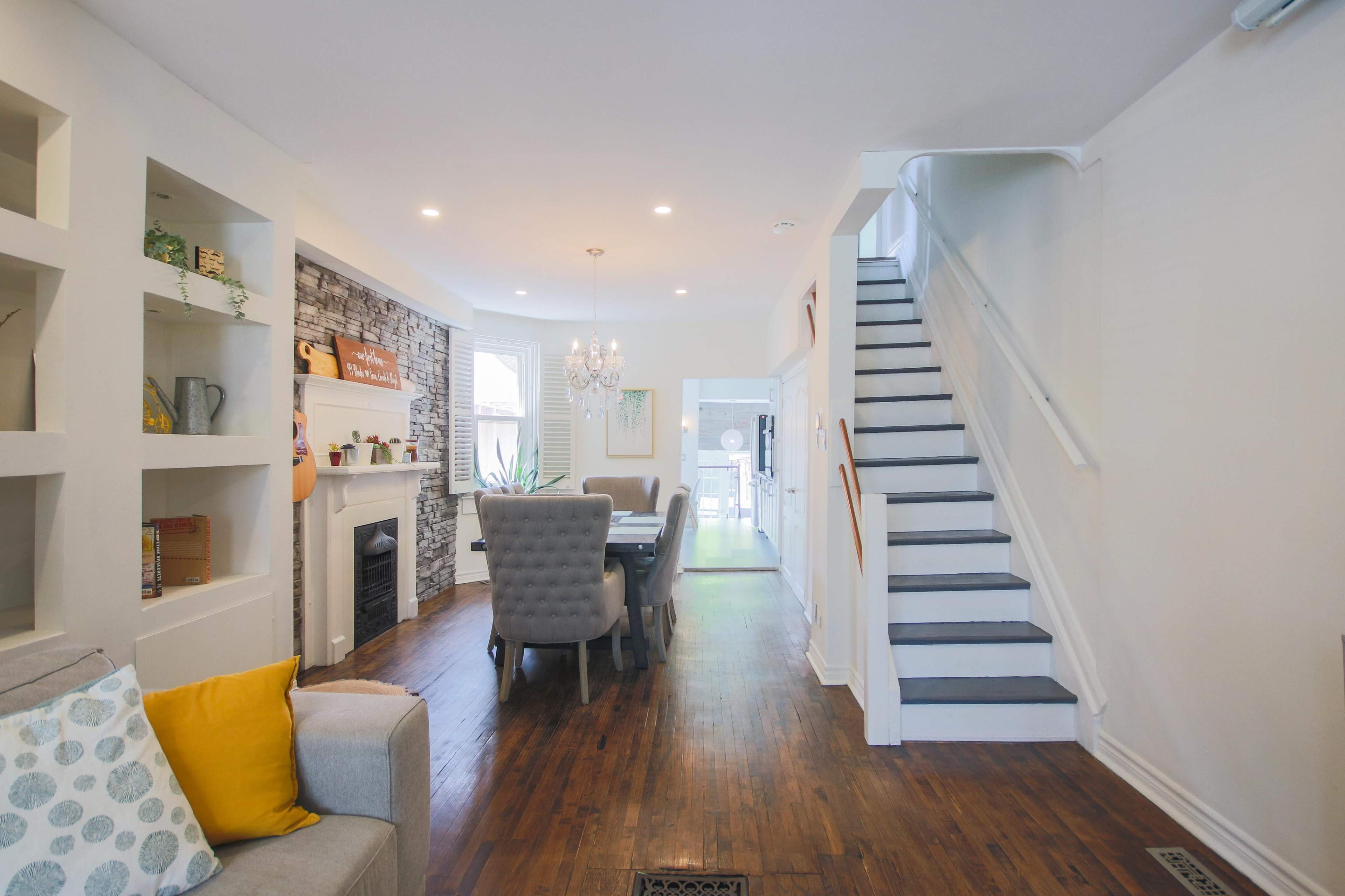 A well-lit open-concept living area with a staircase, dining table, and a fireplace.