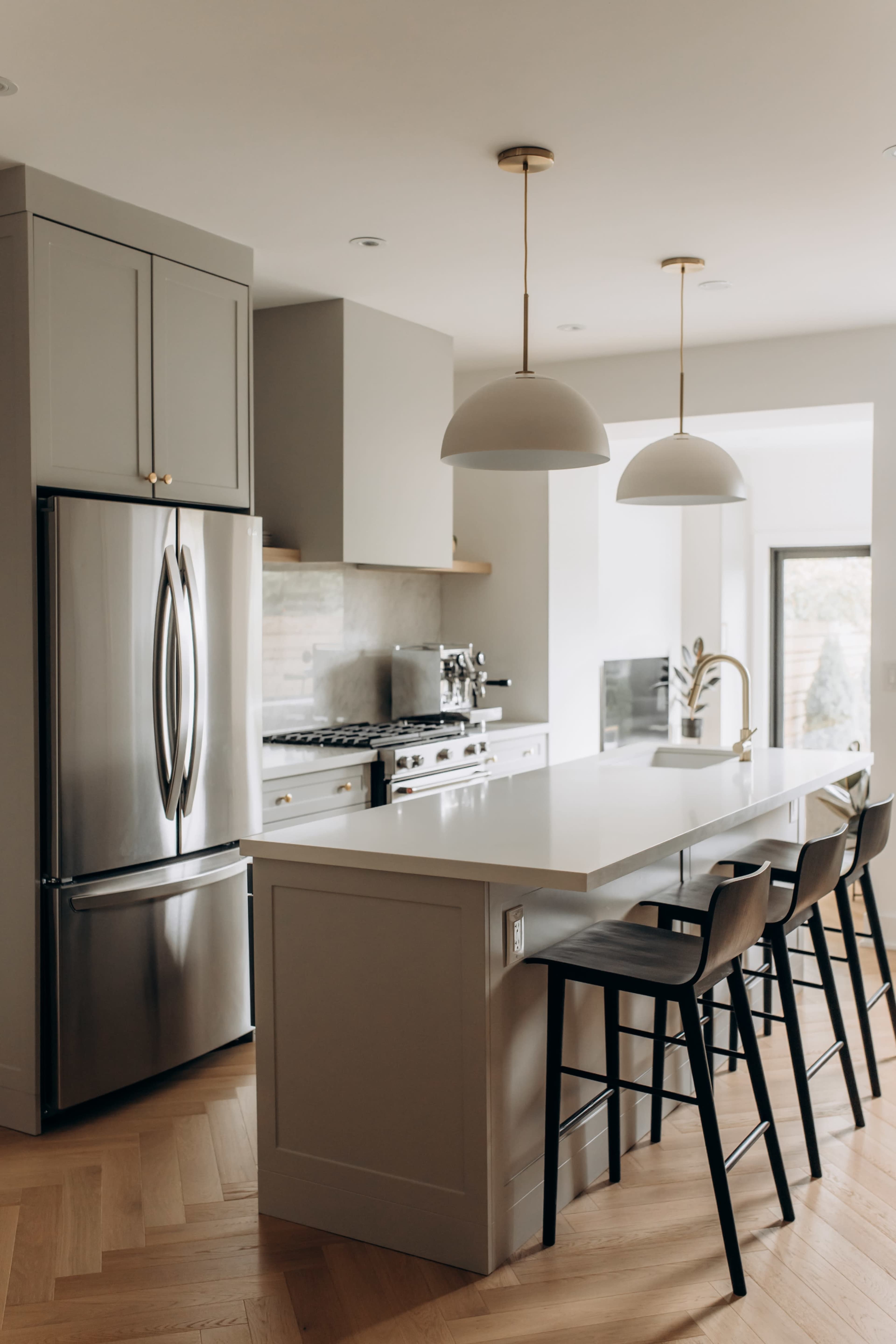 A modern kitchen featuring stainless steel appliances, a large island with seating, and pendant lights hanging above.
