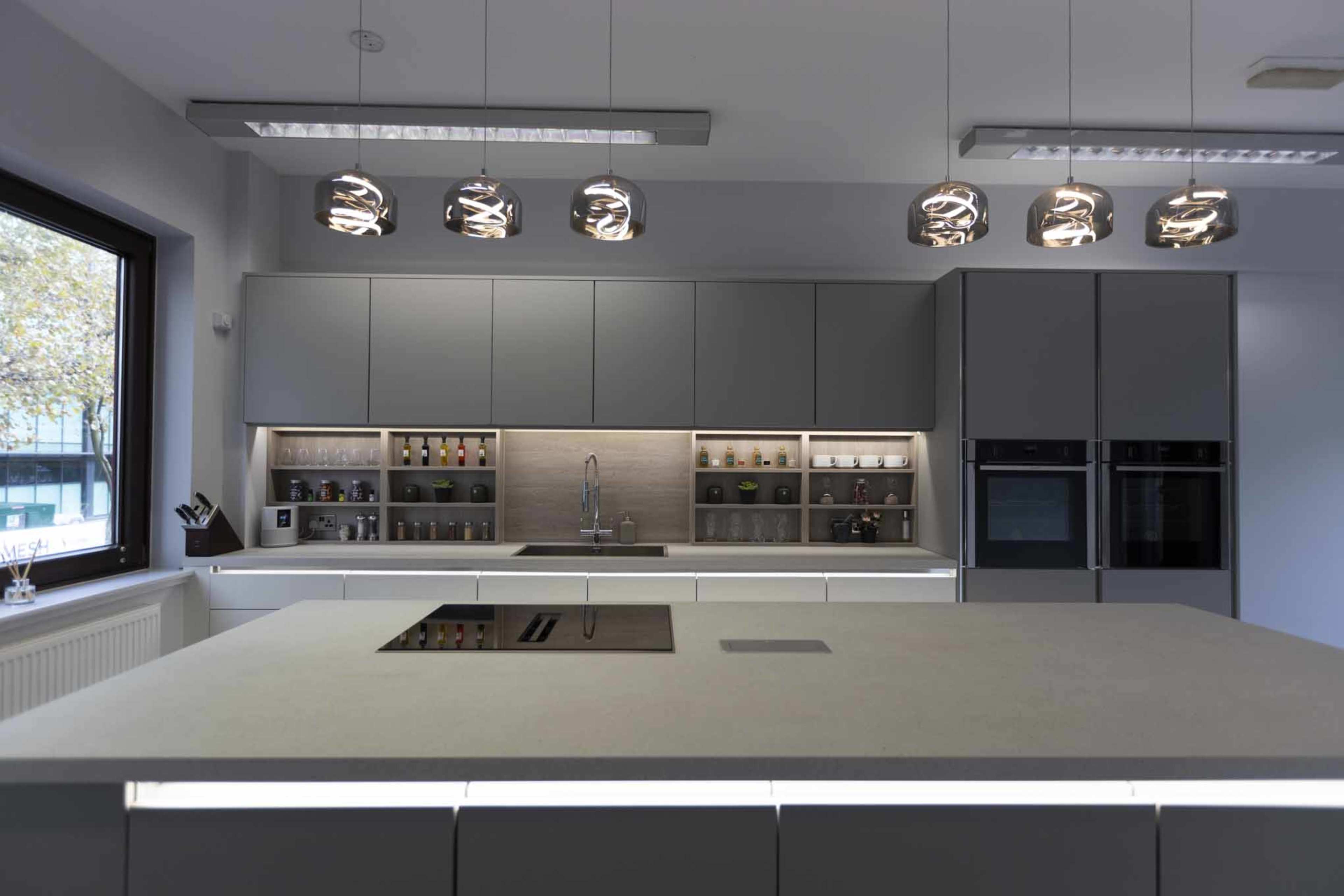 A modern kitchen with gray cabinetry, a central island, and pendant lights above the countertop.