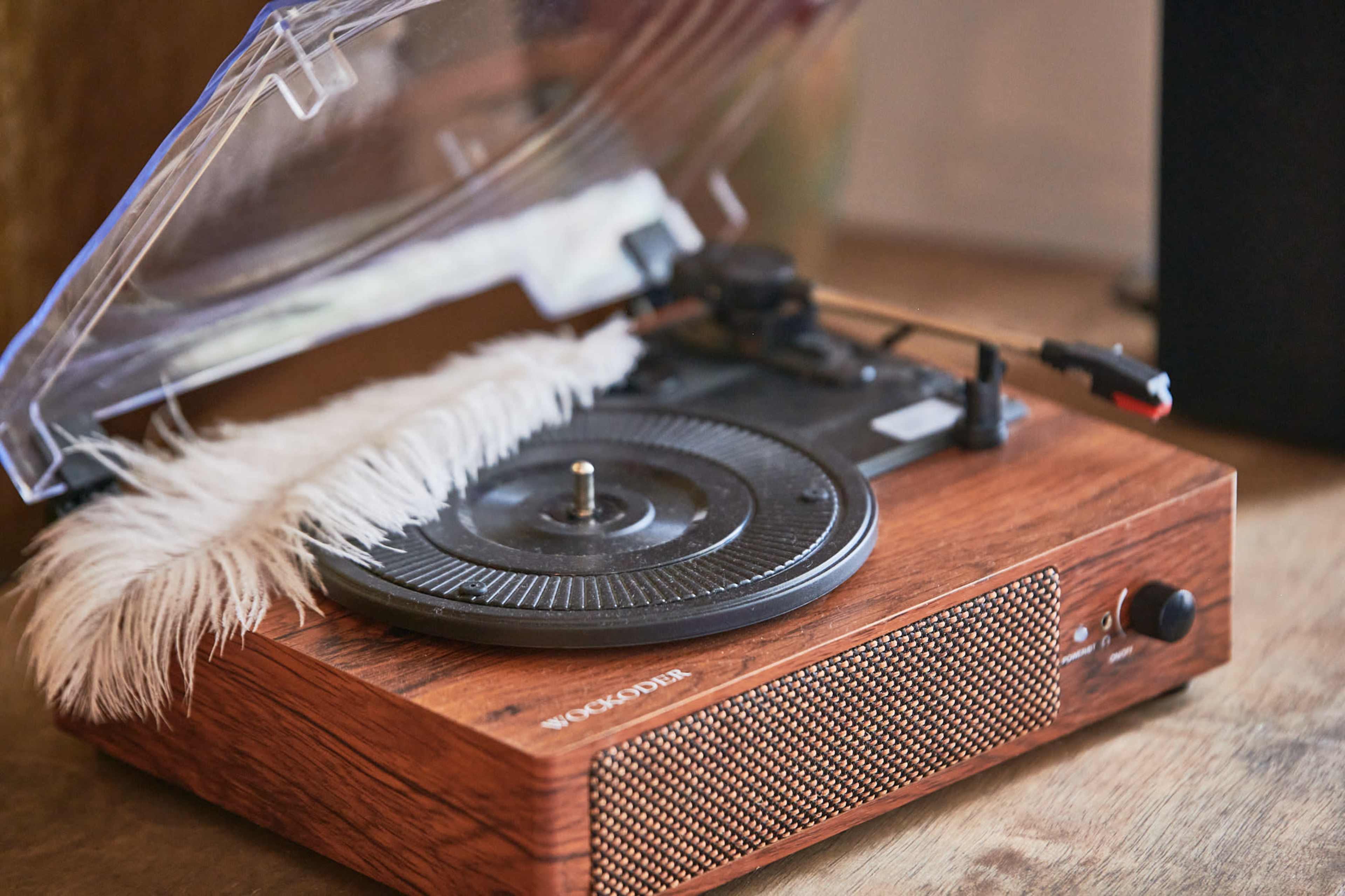 A wooden turntable with a clear cover and a white fur piece on top, placed on a wooden surface.