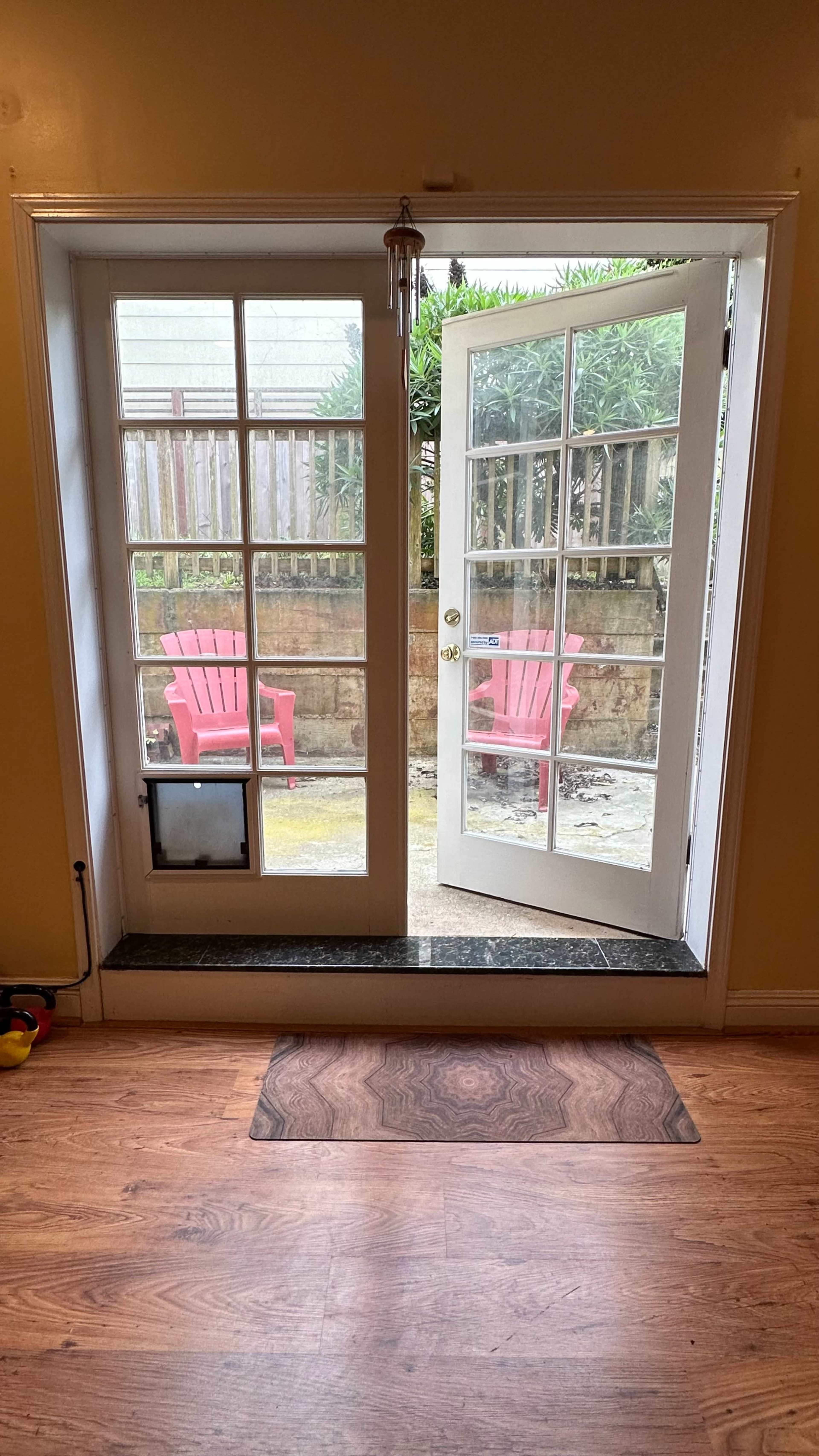 A pair of double doors opens to a small outdoor area featuring two red chairs.