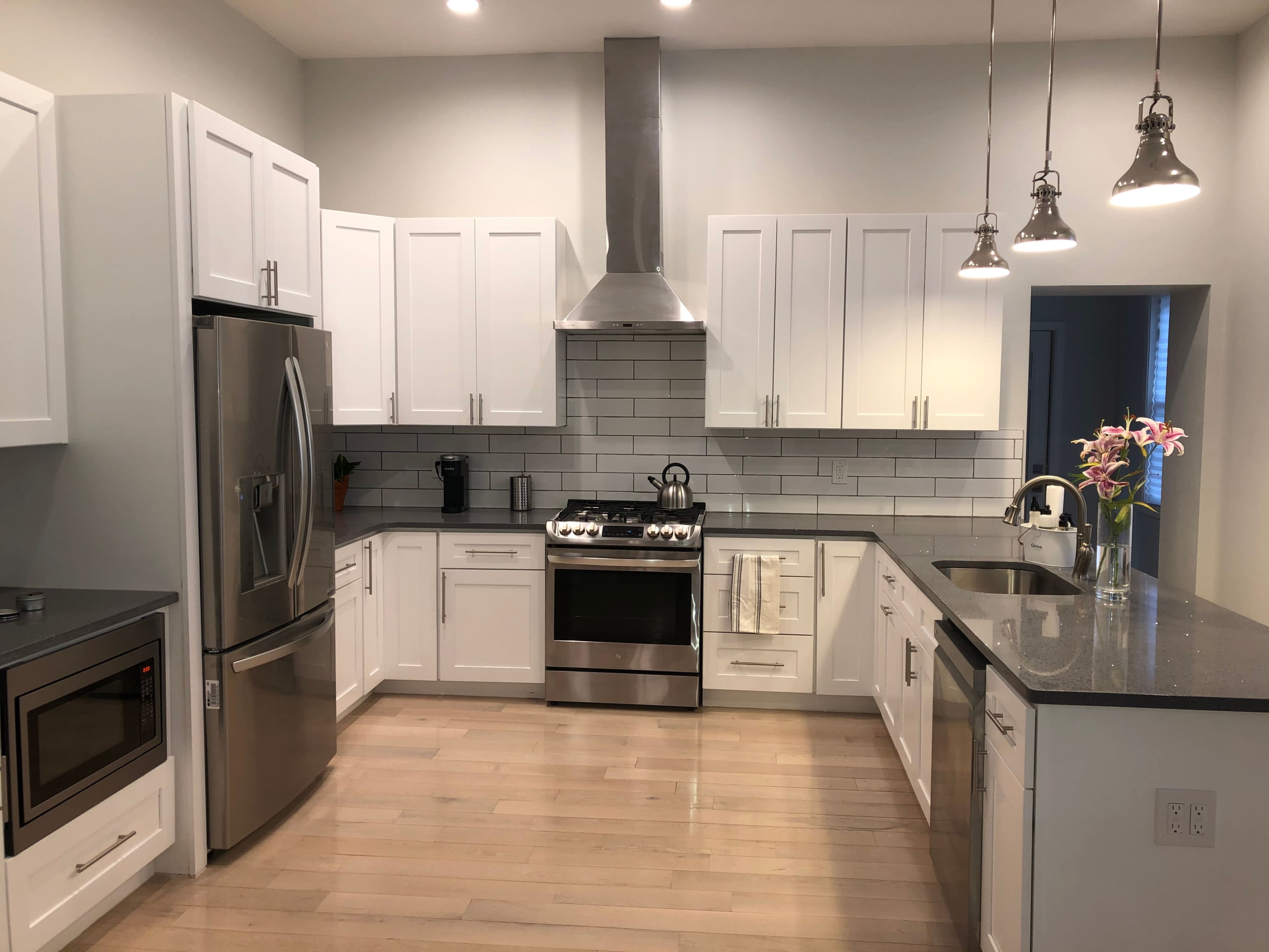 A modern kitchen with white cabinetry, stainless steel appliances, and a gray countertop.