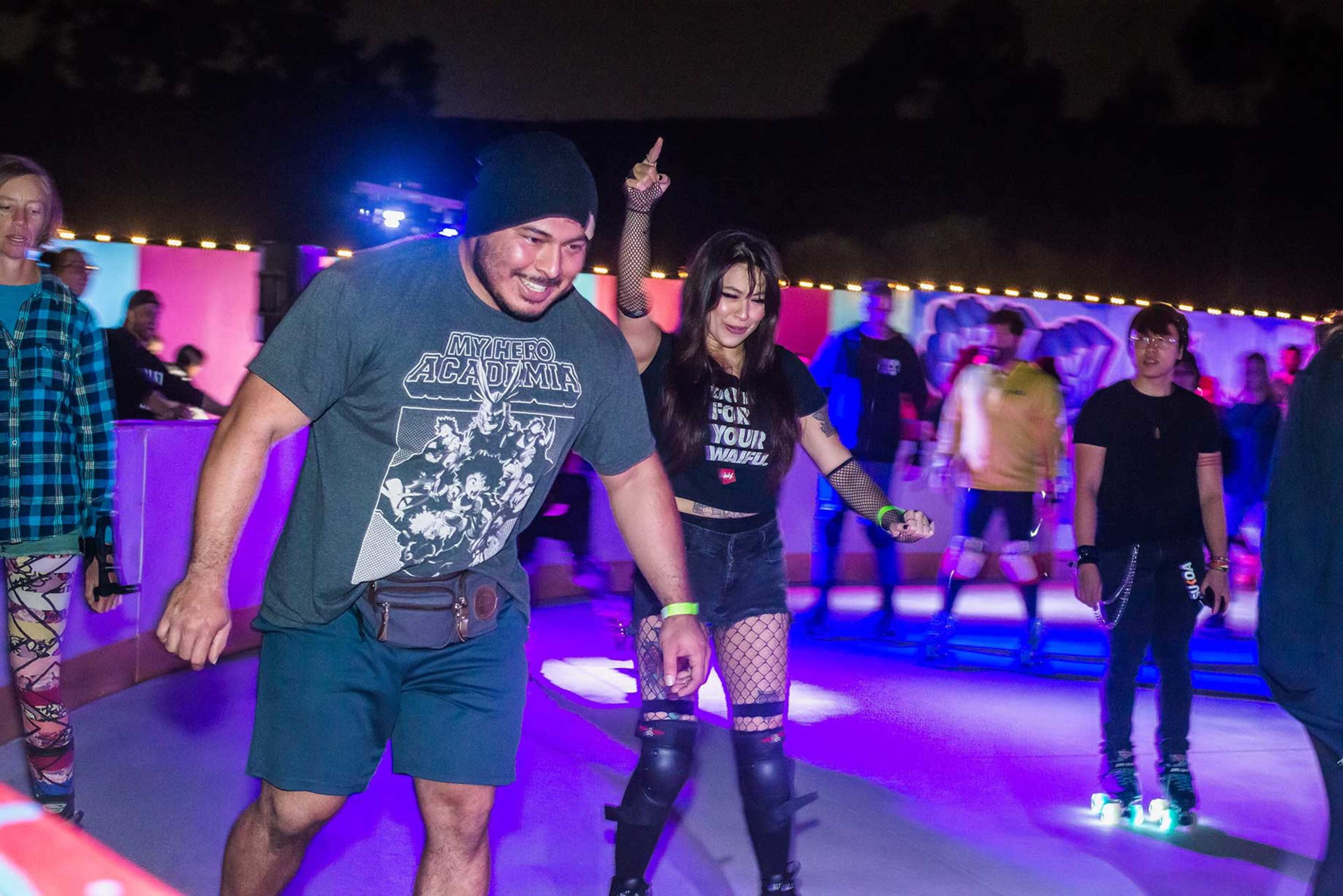 A group of people skate at a brightly lit roller rink during an evening event.