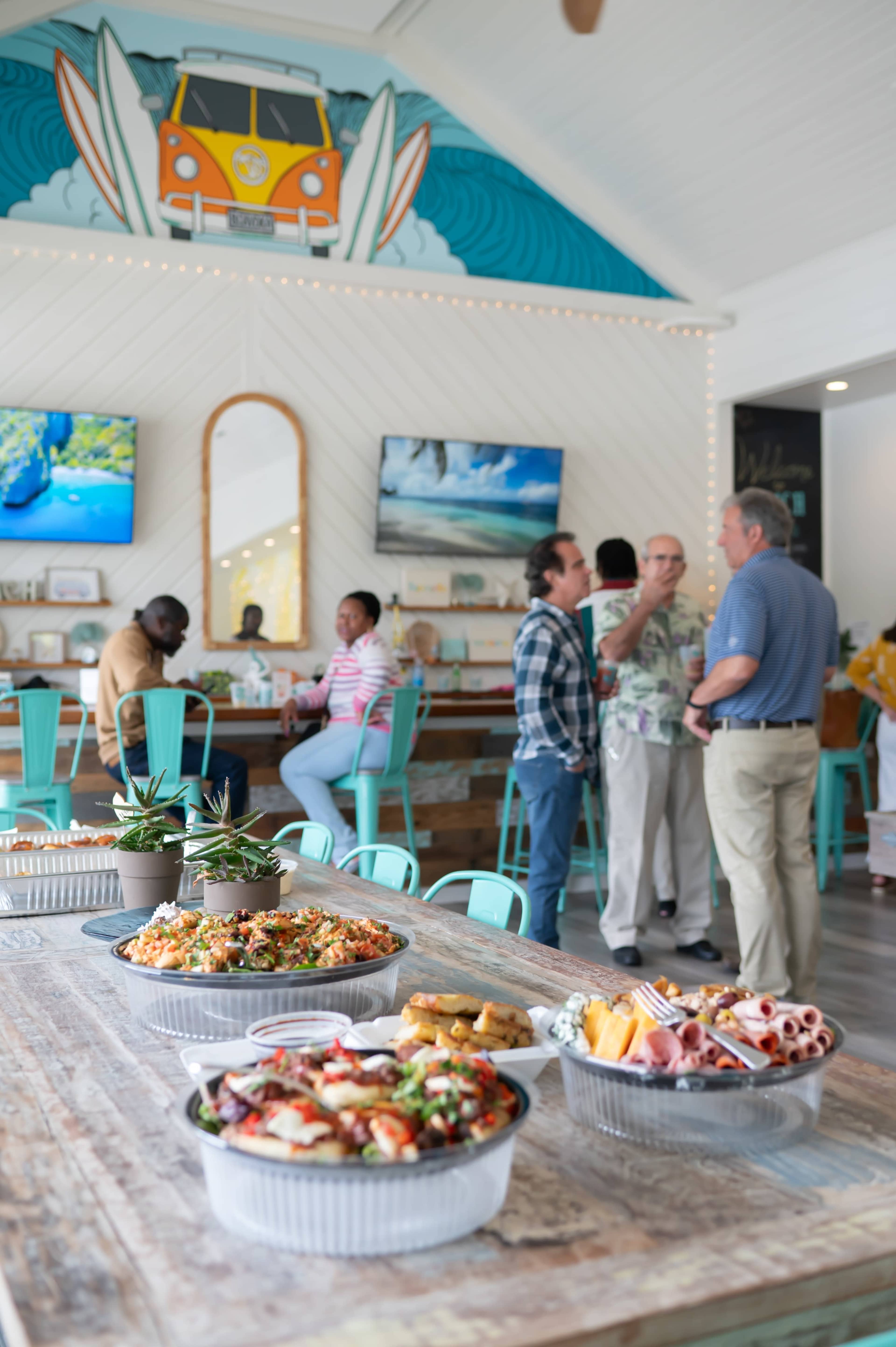People are gathered in a lively restaurant, engaging in conversation around a table filled with a variety of dishes.