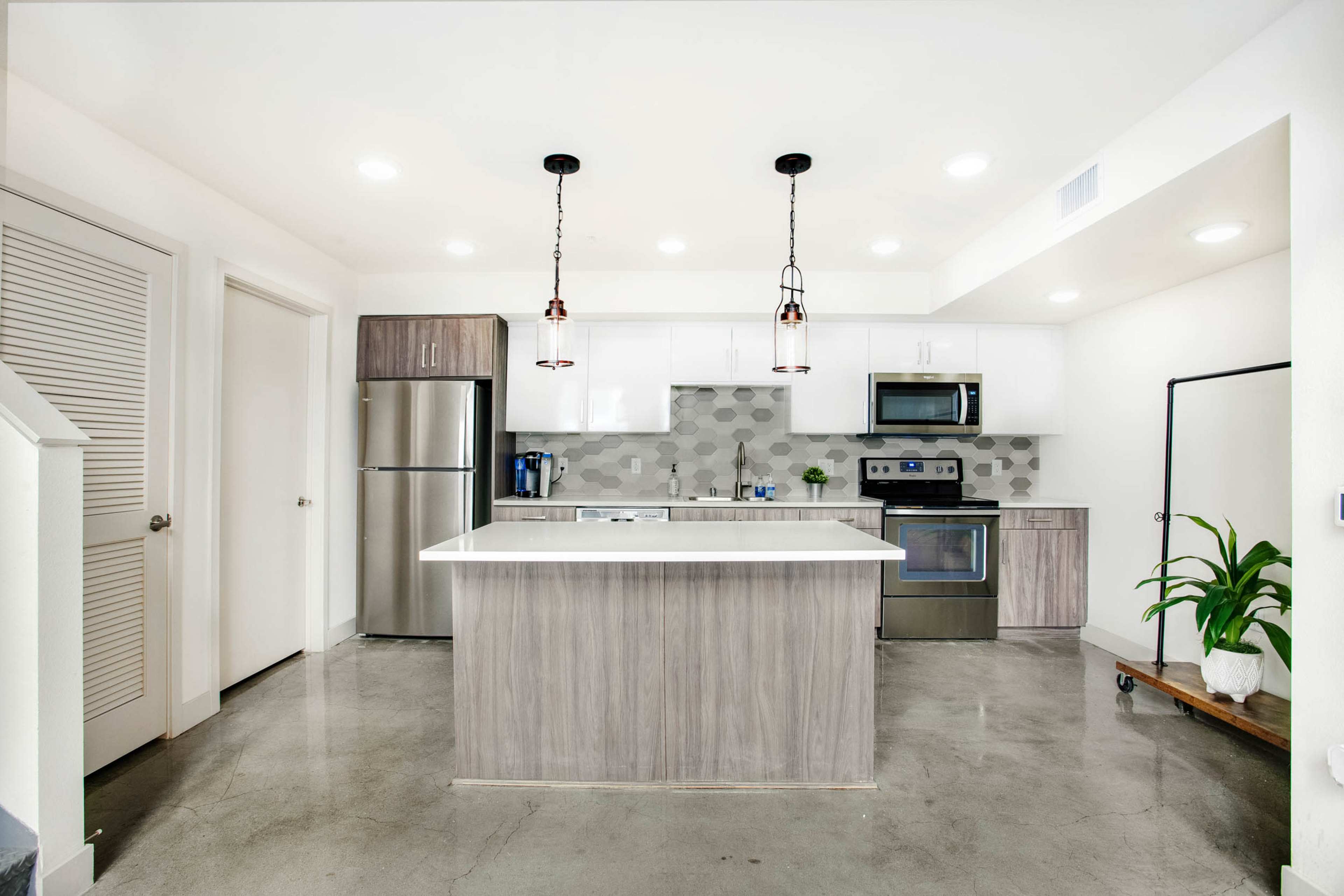 A modern kitchen with a central island, stainless steel appliances, and pendant lighting.
