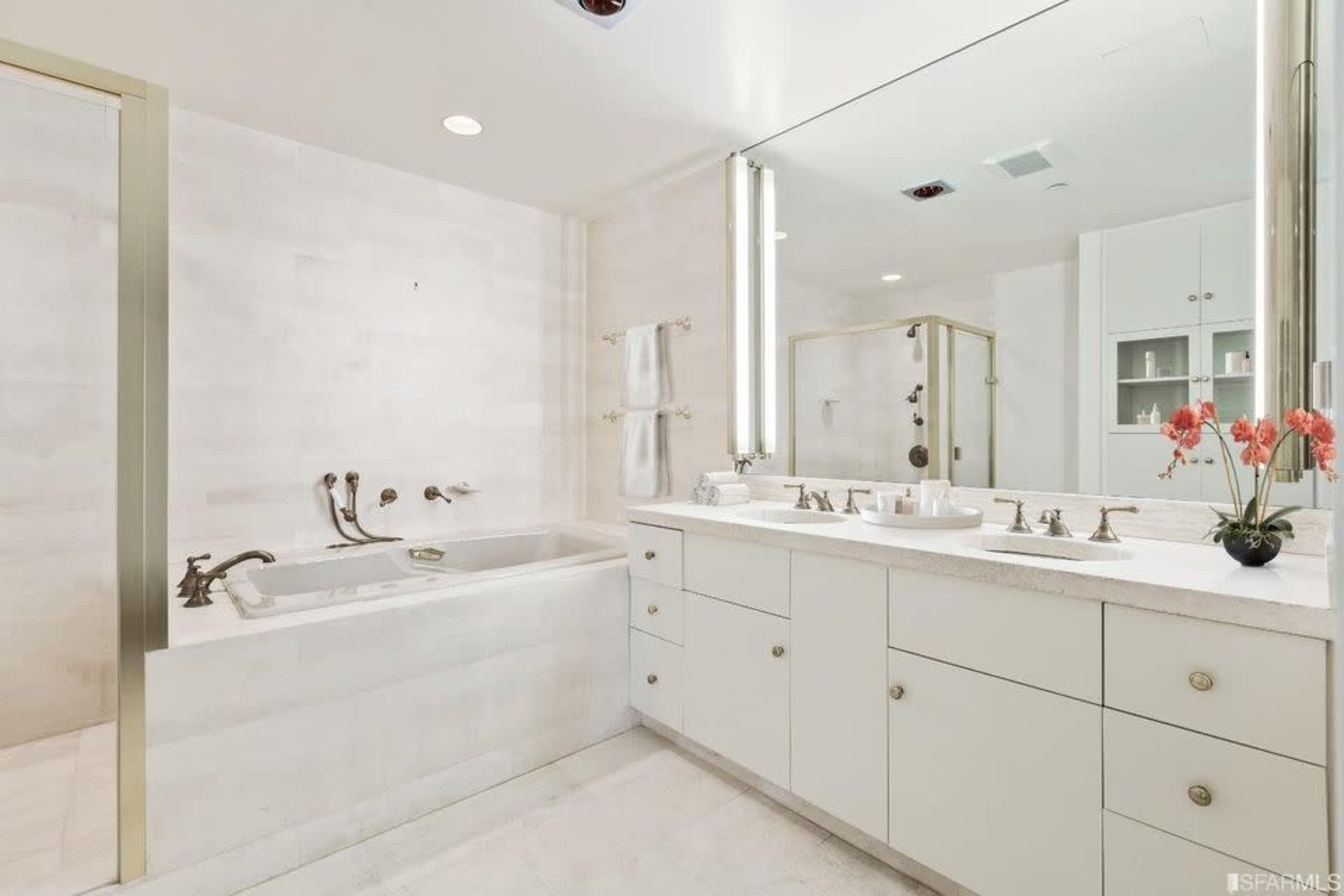 A modern bathroom featuring a dual sink vanity, a separate bathtub, and a large mirror with soft lighting.
