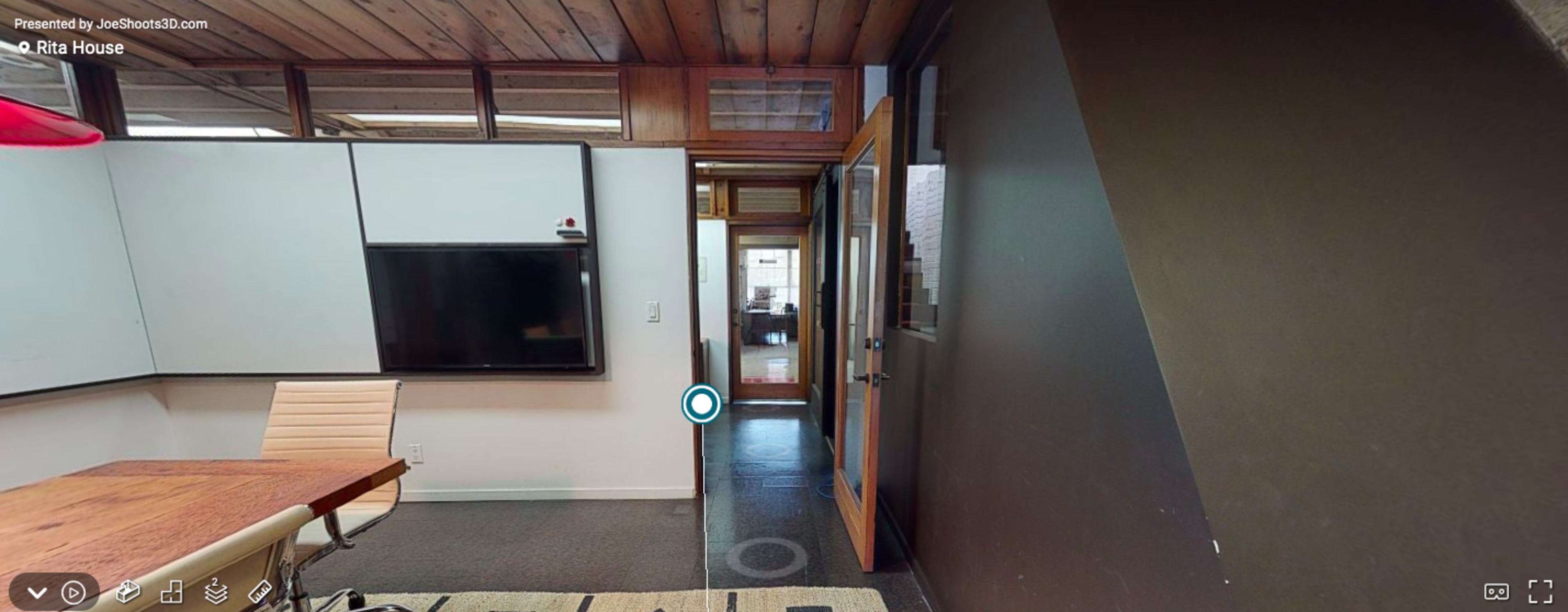 An interior view of a modern room with a wooden ceiling, a glass door, and a television mounted on the wall.