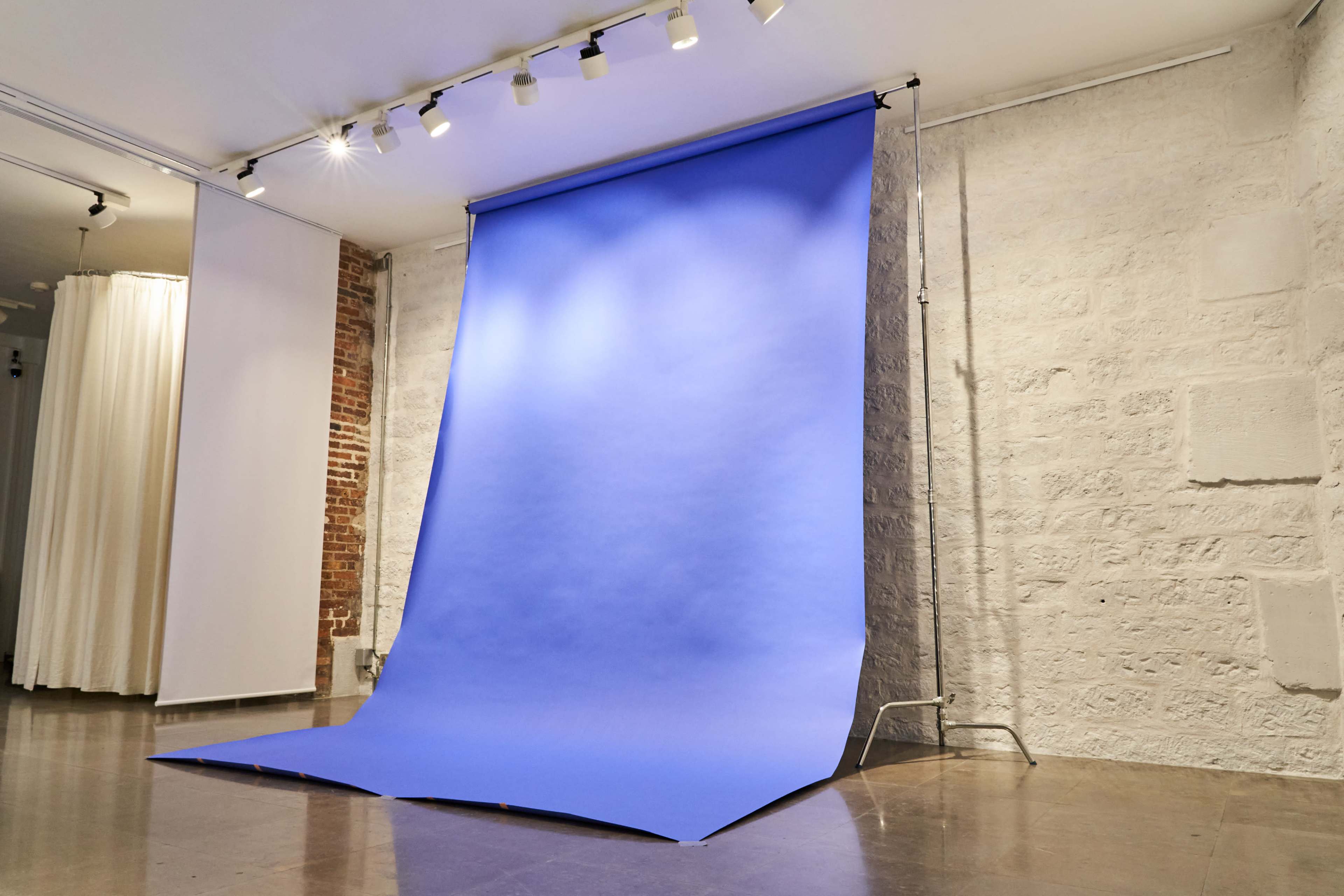The image shows a photography studio with a large blue backdrop set up against a wall.