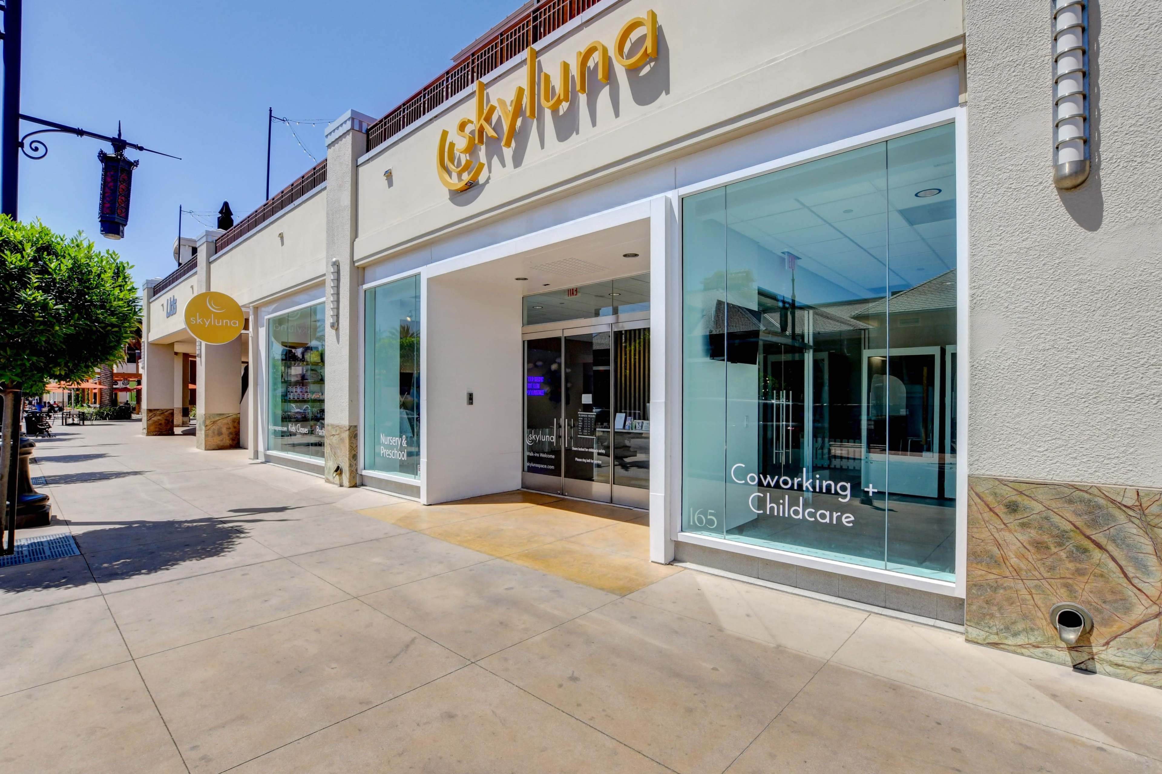 A modern storefront with large glass windows displaying the words "Coworking - Childcare" above the entrance.