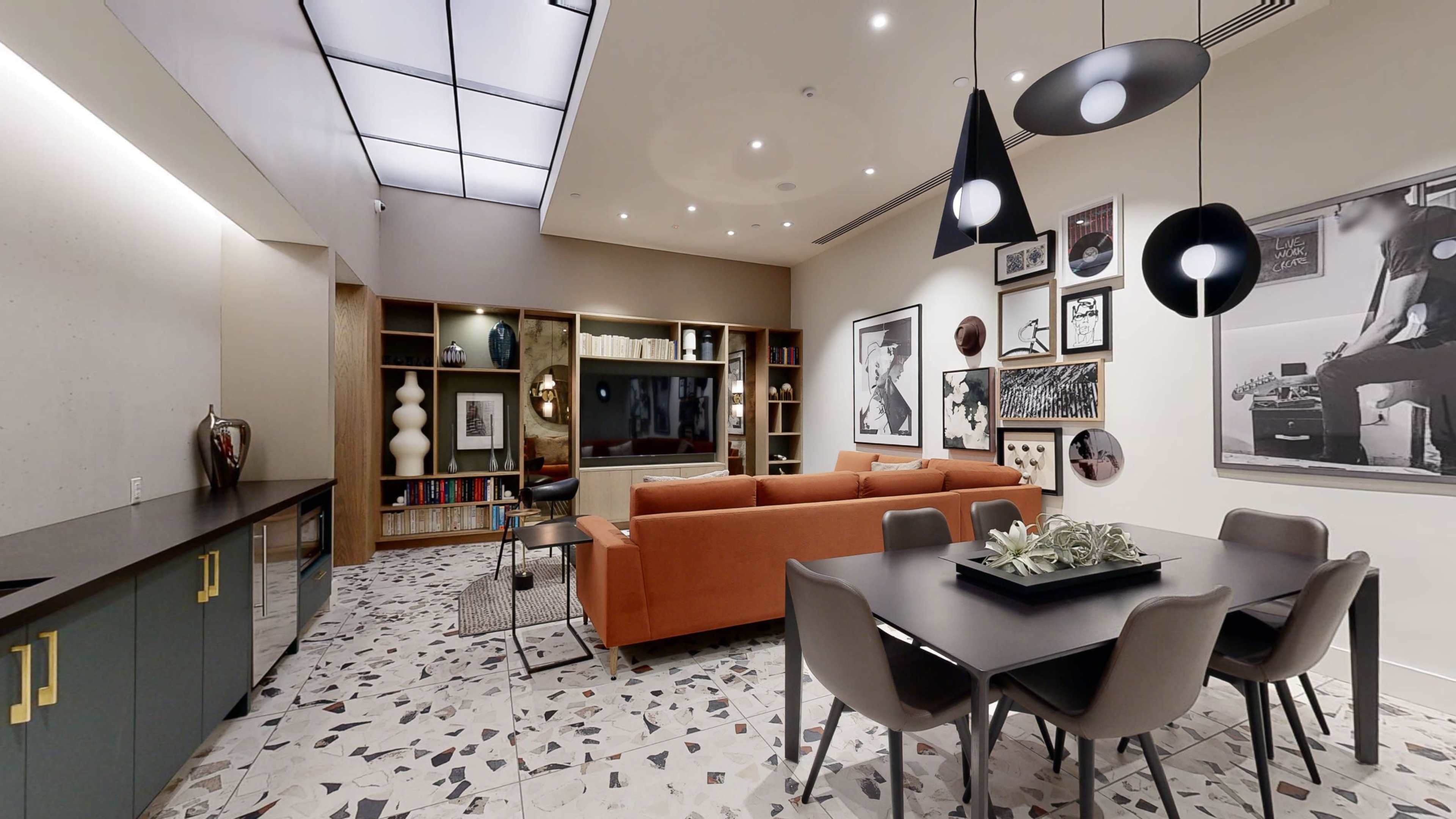 A modern living room and dining area with a sectional sofa, dining table, and various decorative elements against a backdrop of a patterned floor.