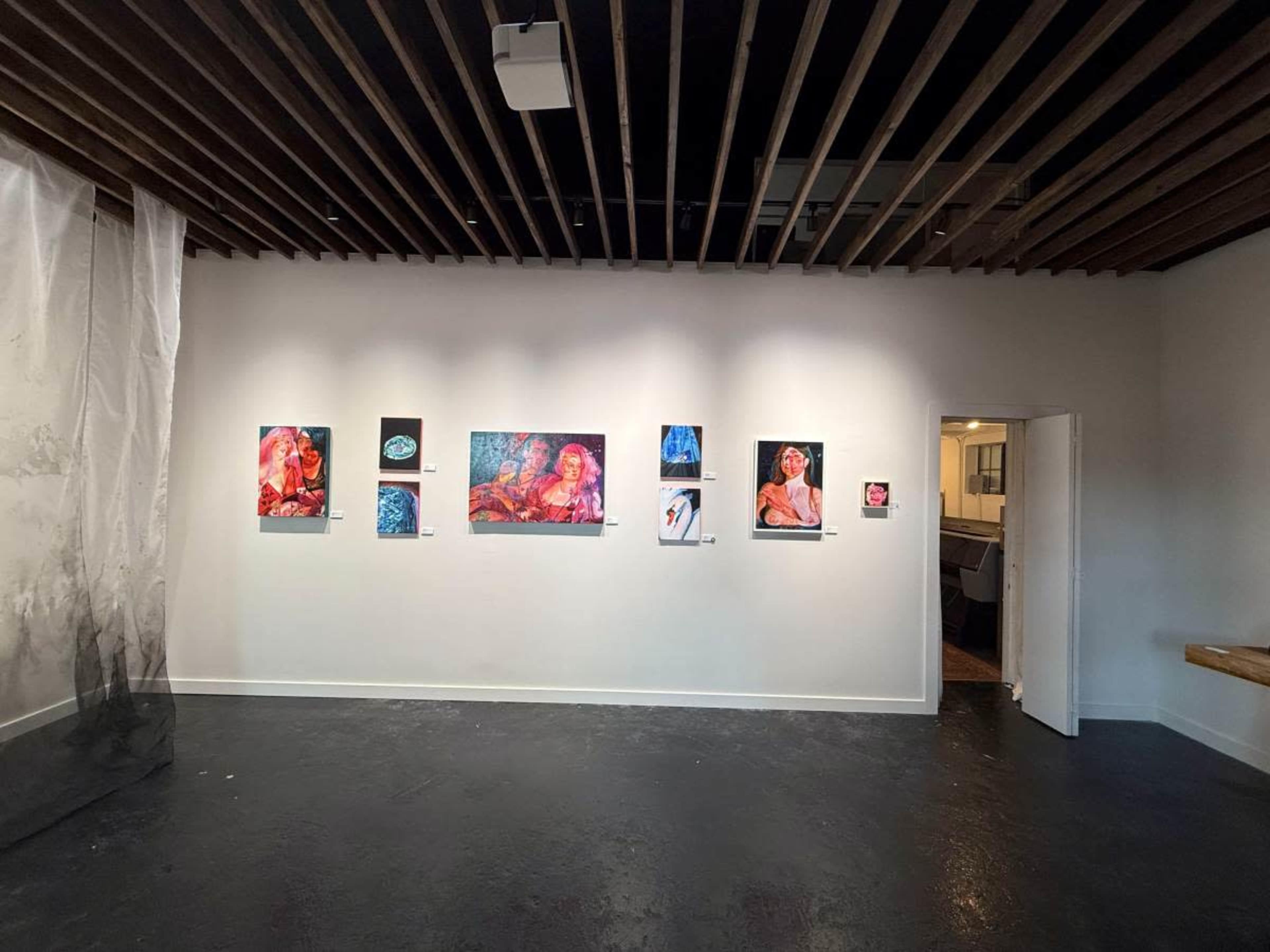 The image shows an art gallery wall displaying a series of framed artworks, with a doorway leading to another room in the background.