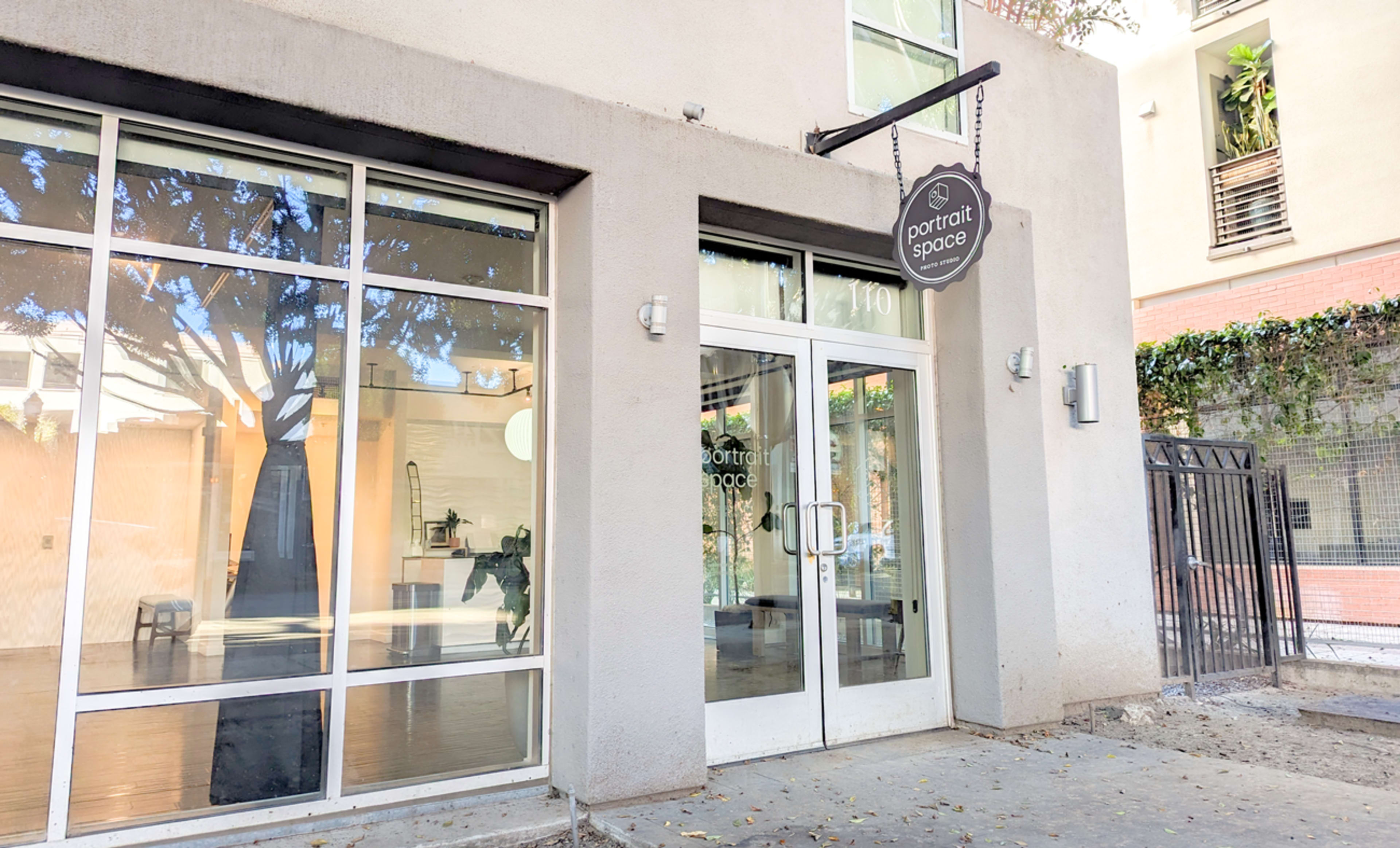 The entrance of a building labeled "portrait space," featuring large glass windows and a modern design.