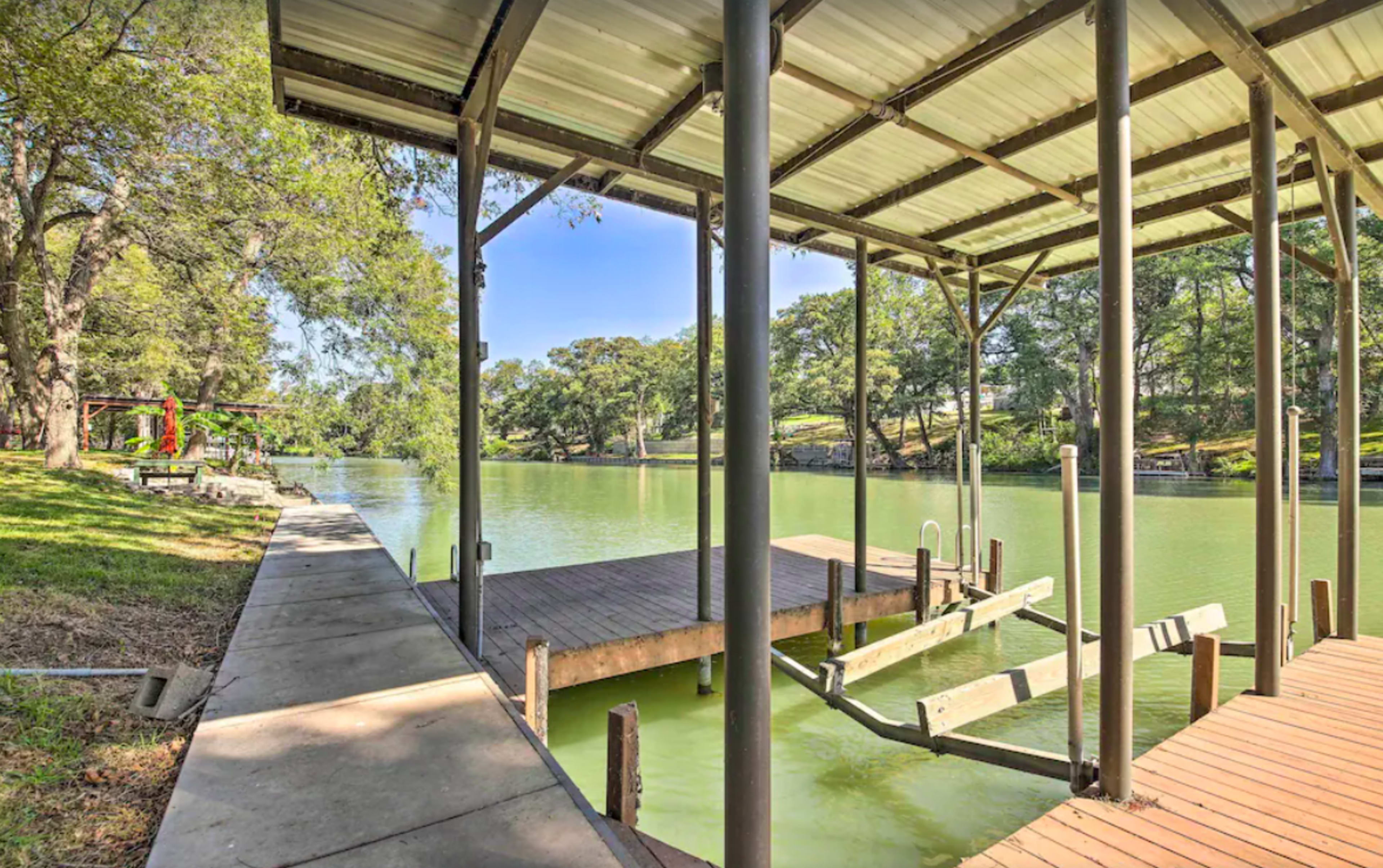 A covered dock on a calm green river surrounded by trees.