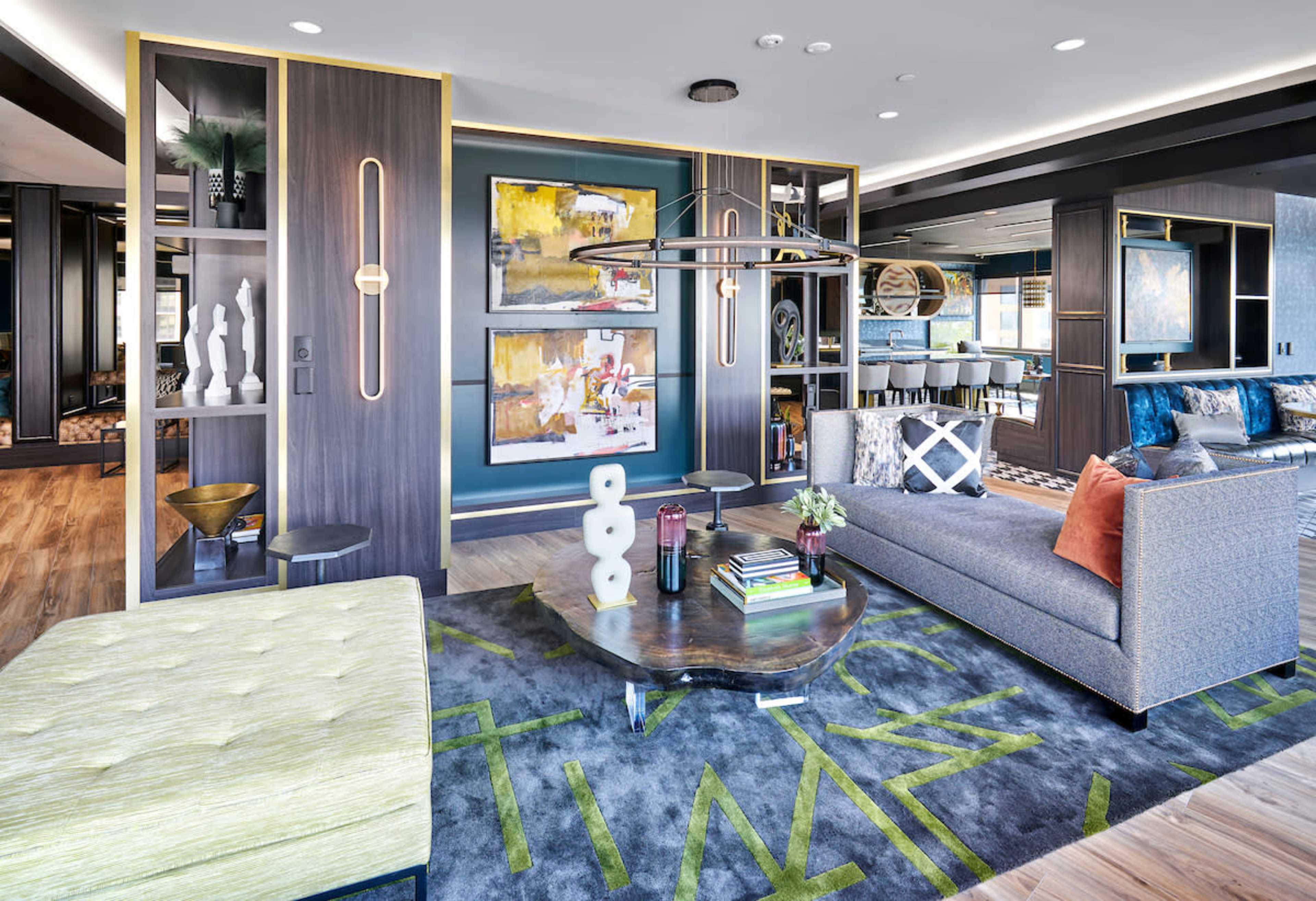 A modern living room with a gray sofa, a round coffee table, an area rug featuring geometric patterns, and wall art arranged within stylish shelving units.