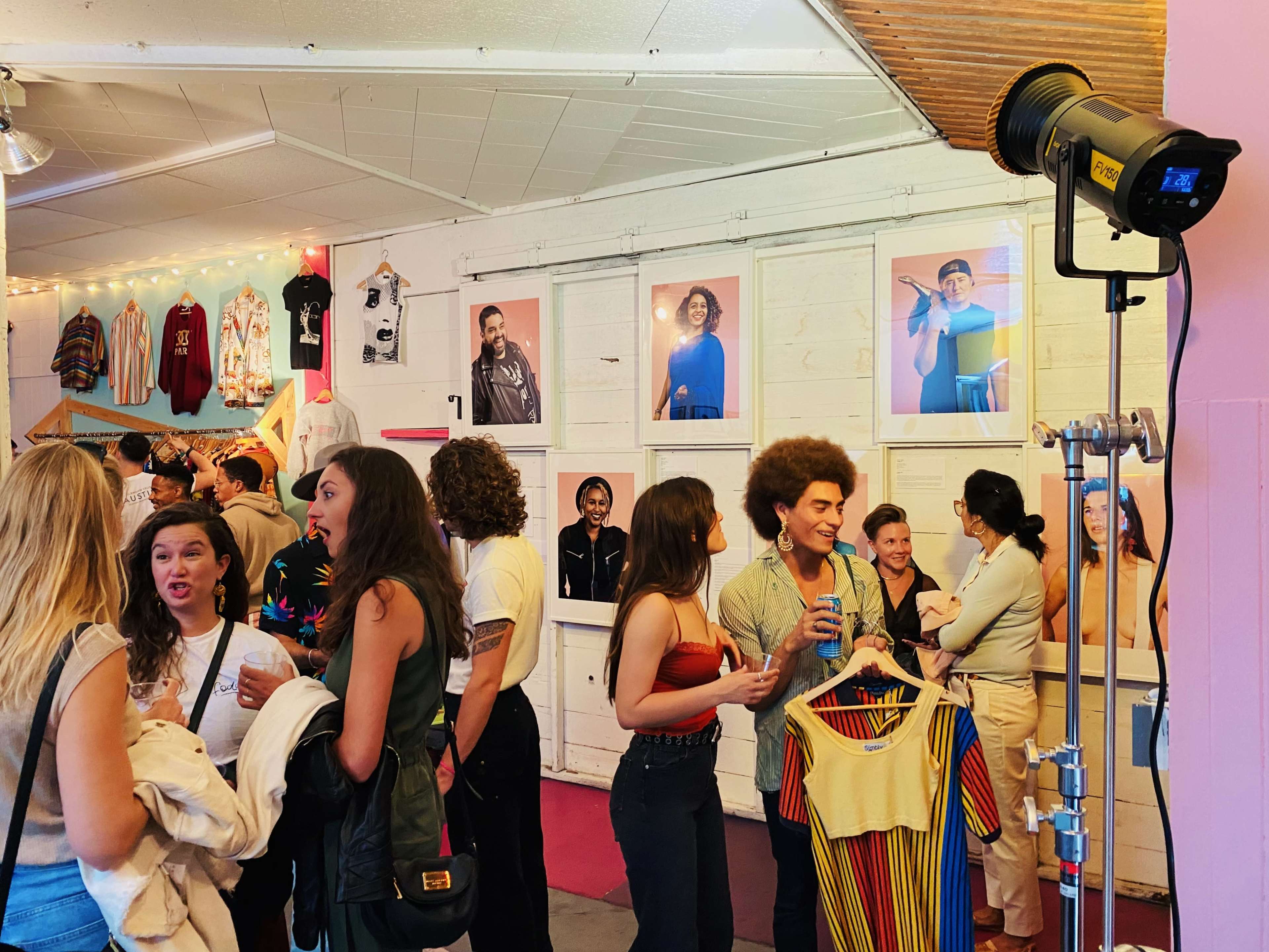 A group of people socializes in a gallery displaying framed photographs on the walls.