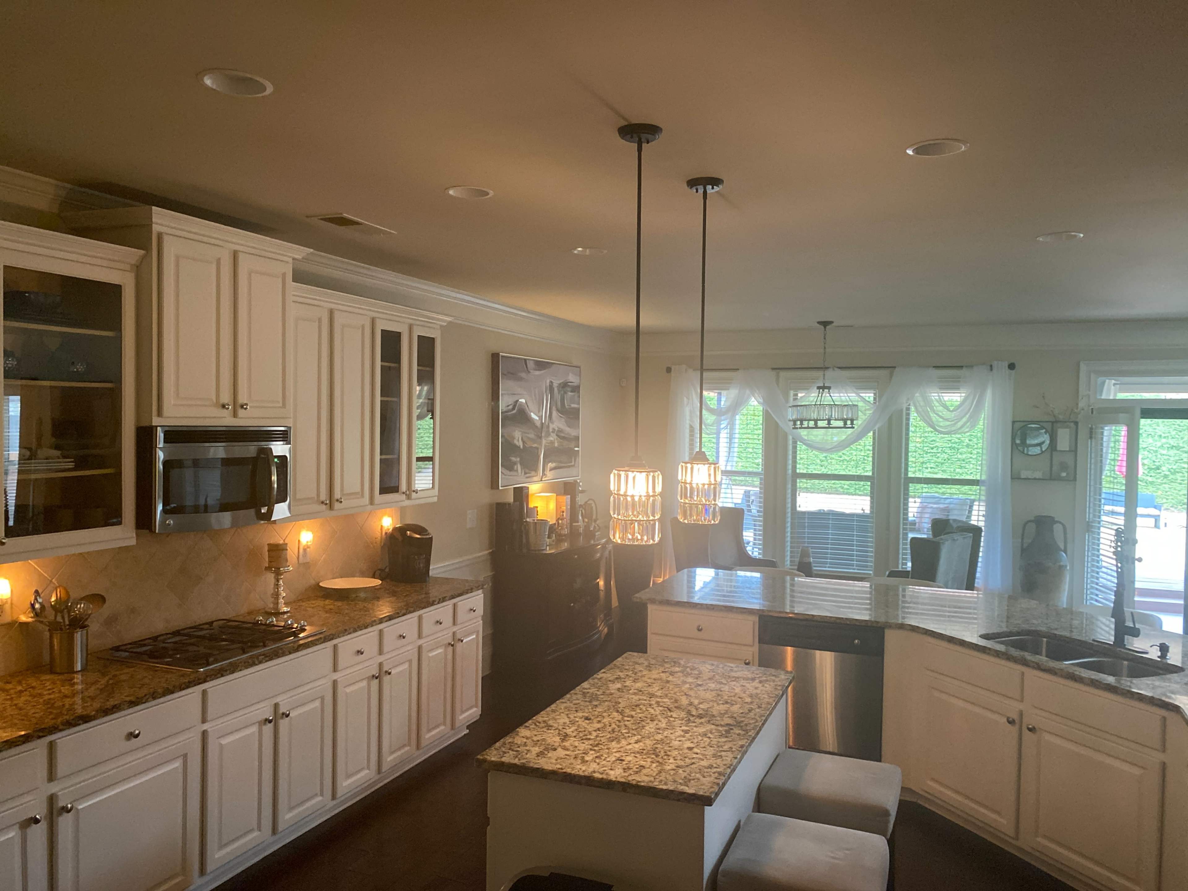A modern kitchen with white cabinetry, granite countertops, and a central island with pendant lighting.