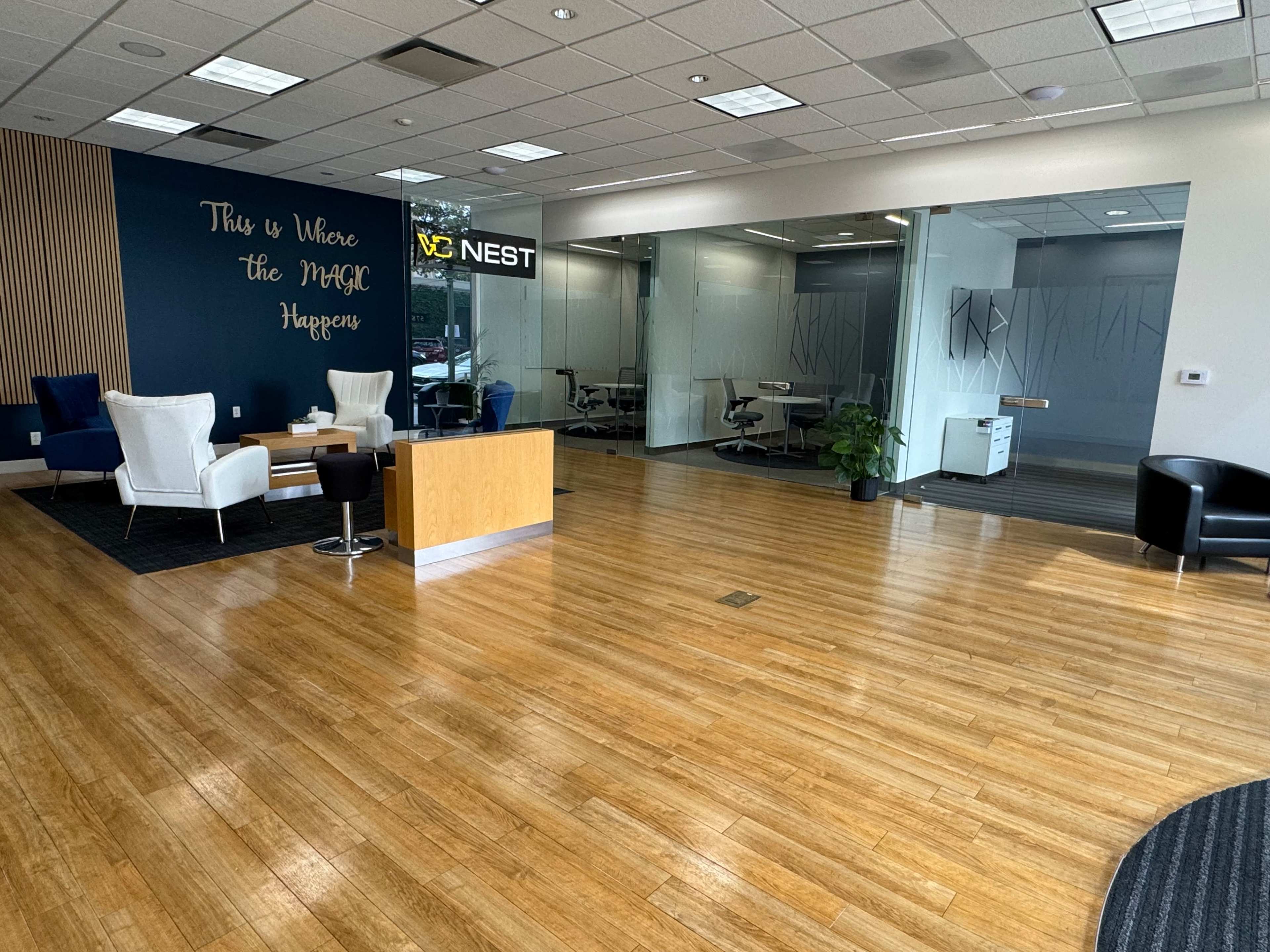 The scene shows a modern office lobby with a reception area, seating, and glass-walled conference rooms.