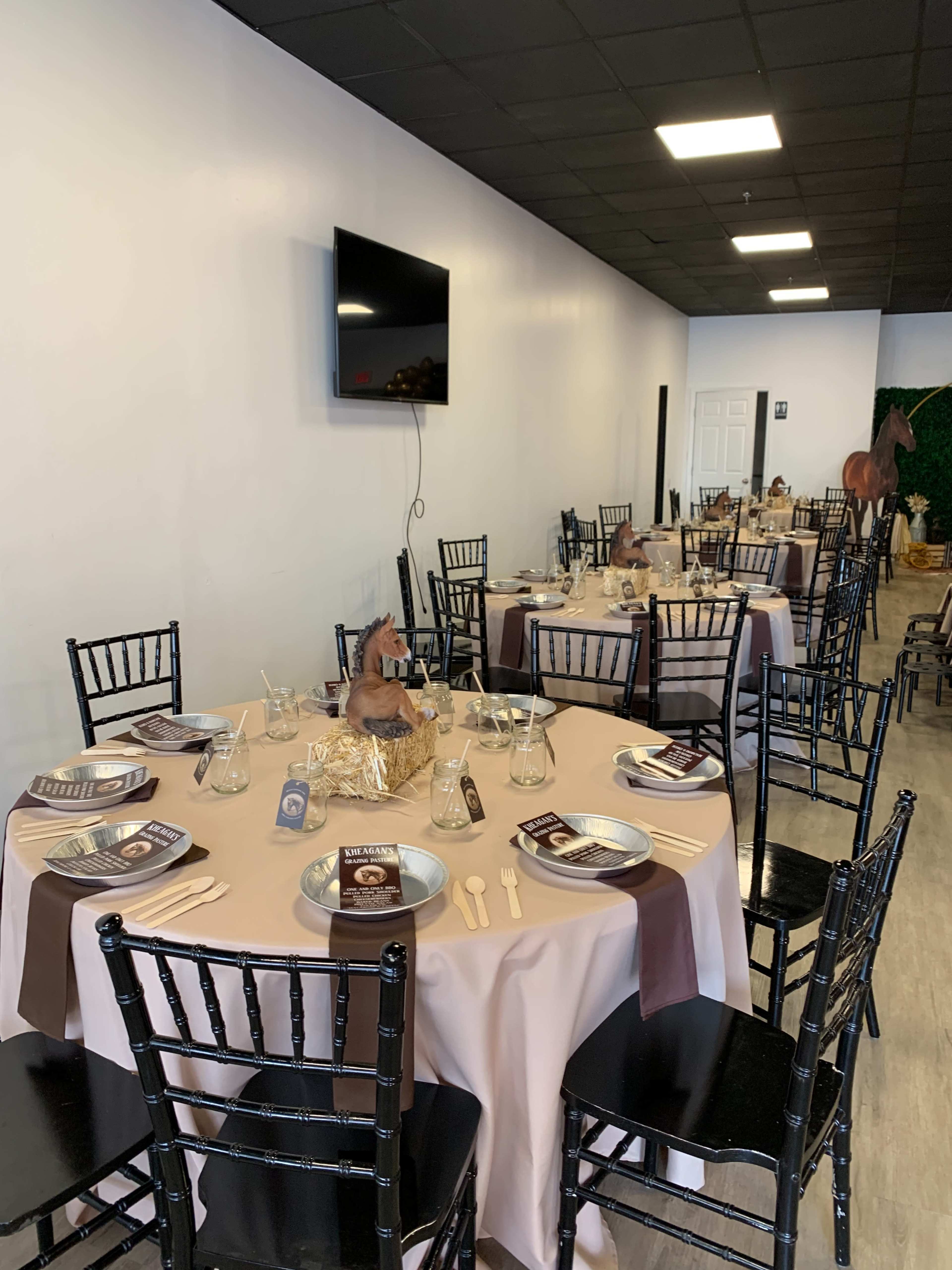 A banquet hall is set up with several elegantly arranged tables, each featuring place settings and decor in a neutral color scheme.