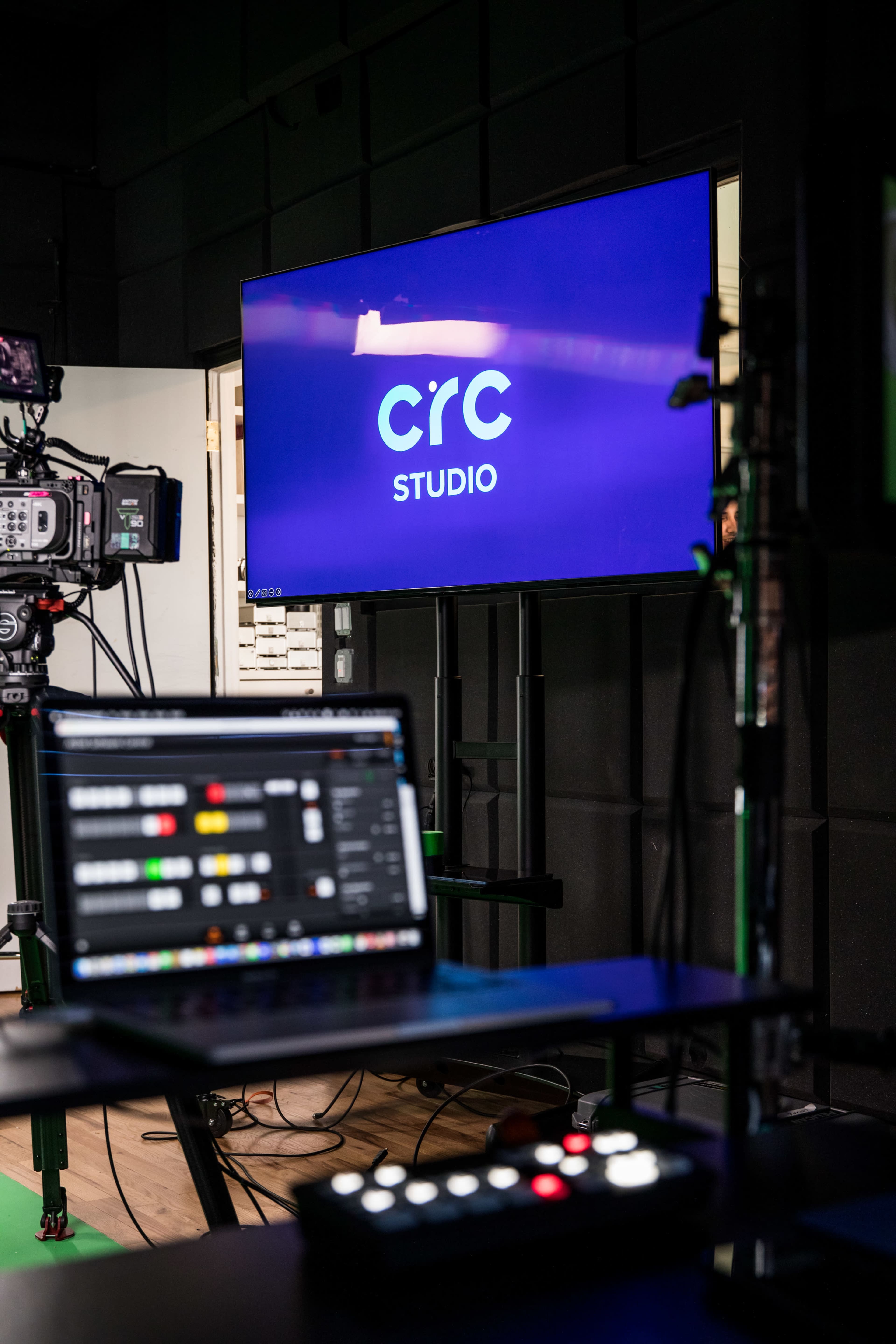 A television screen displaying the logo for "CRC Studio" and a laptop with a control interface in the foreground.