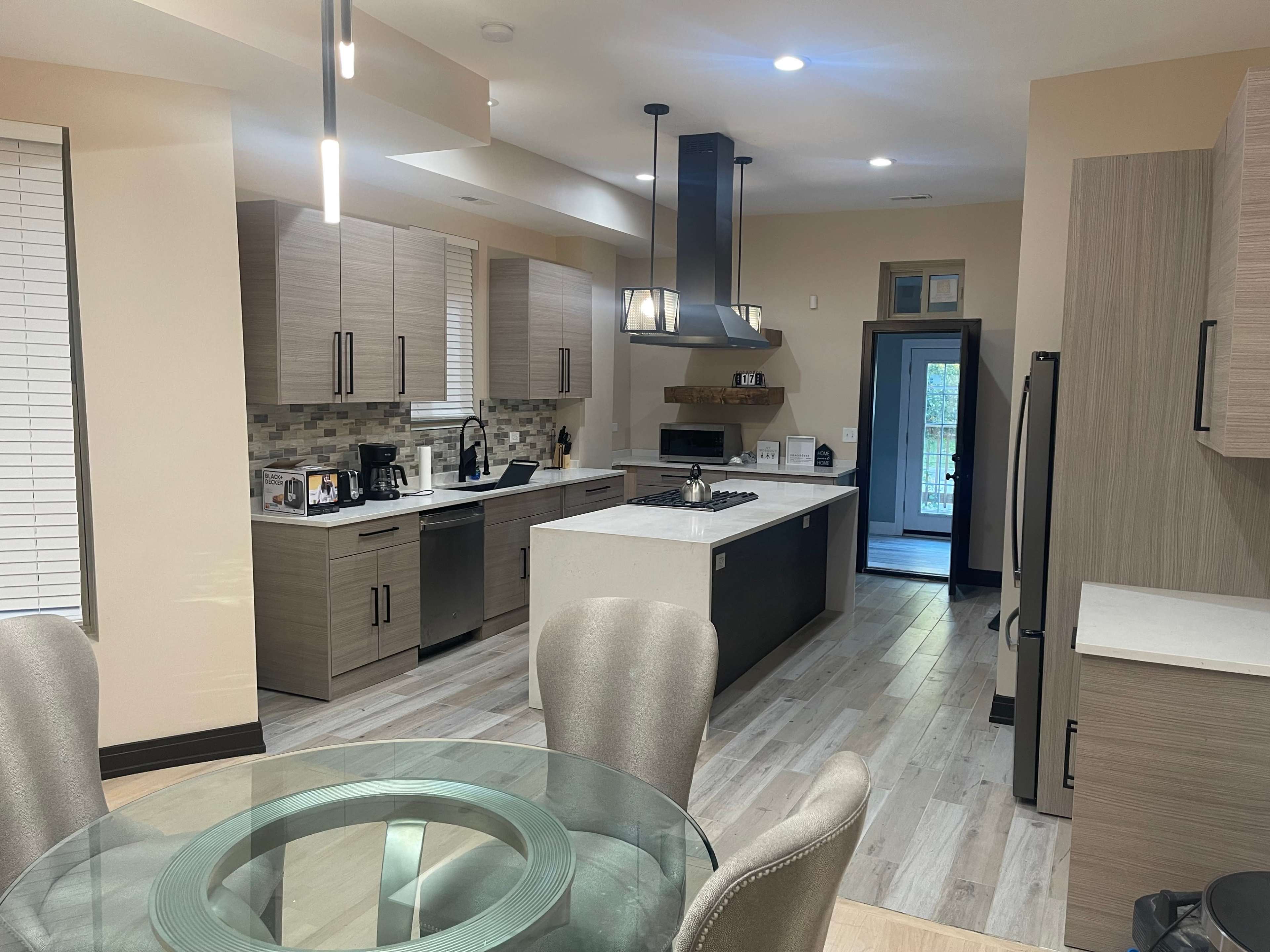 A modern kitchen featuring wooden cabinets, a large island with a gas stove, and stainless steel appliances.