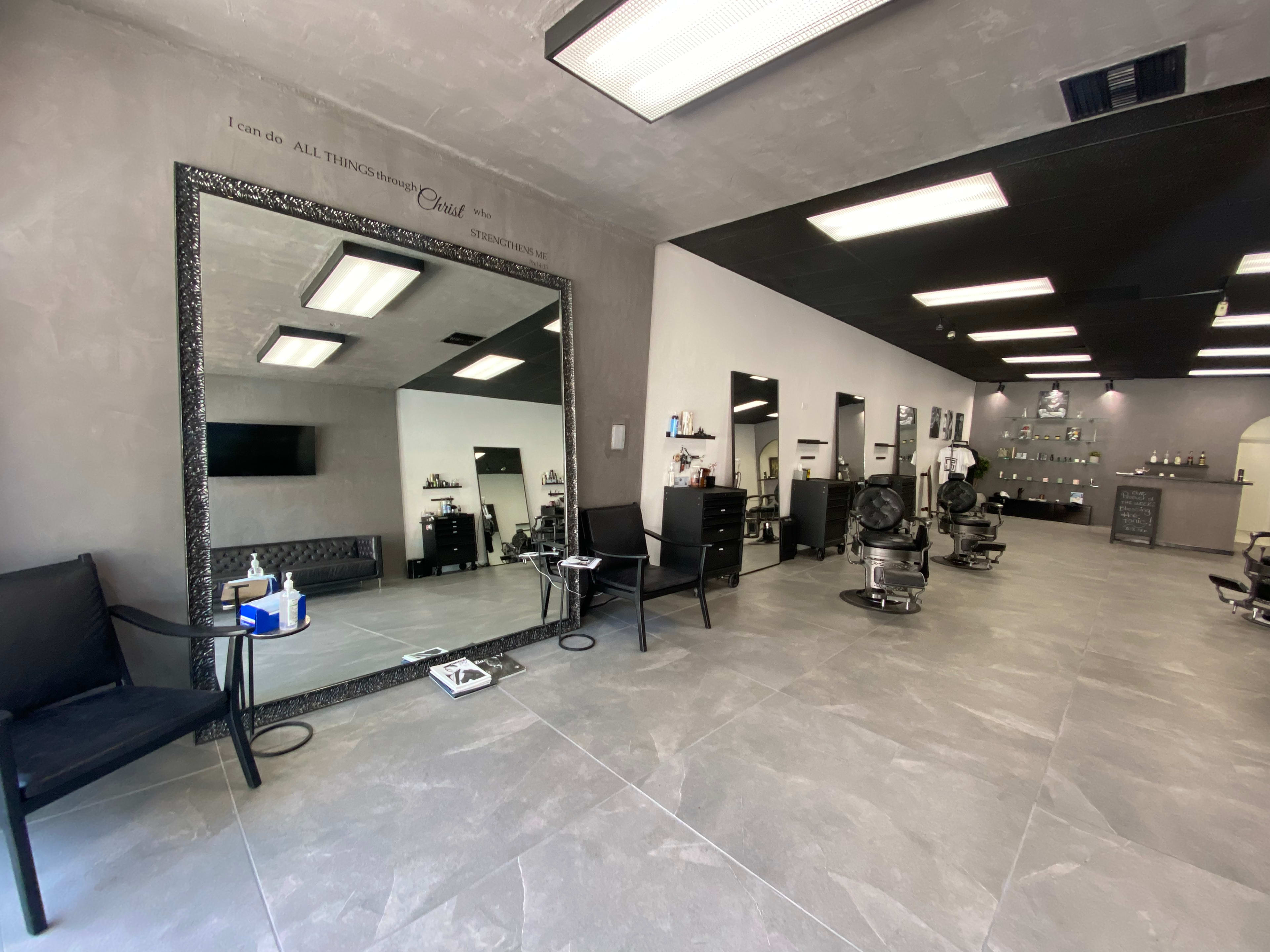 A modern hair salon with several styling stations, a large mirror, and sleek, tiled flooring.