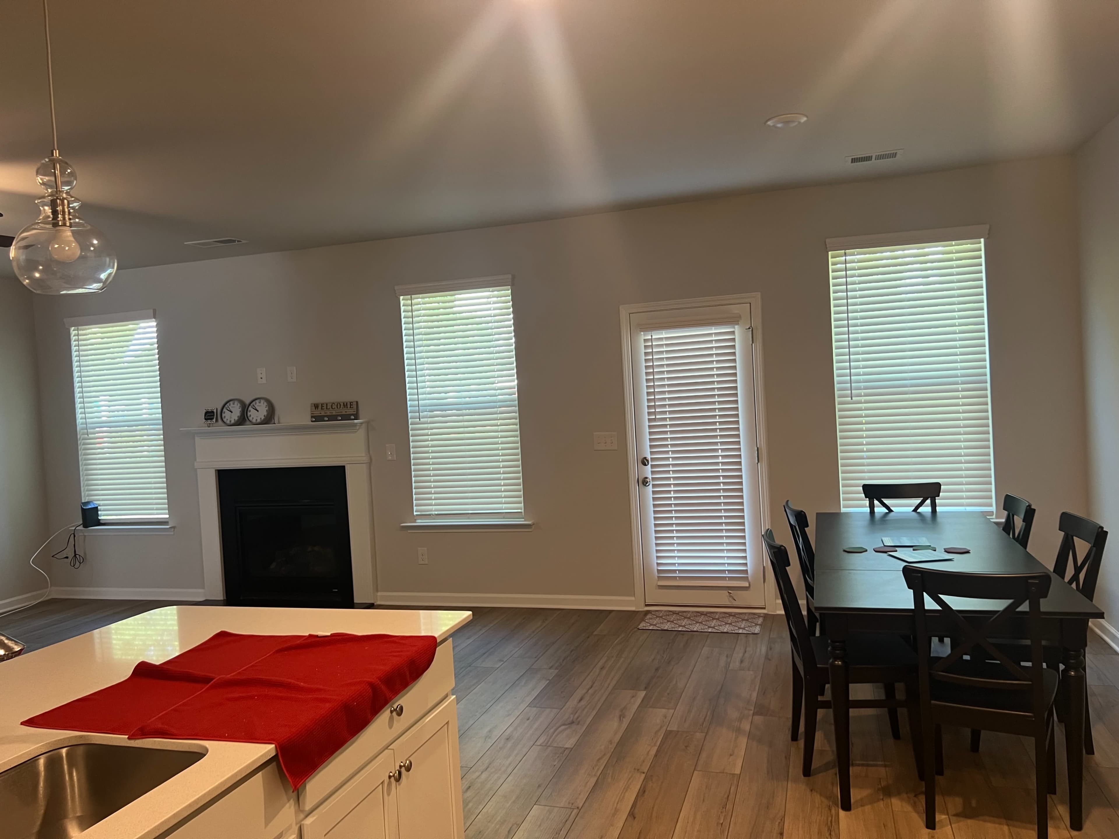 A modern kitchen and dining area with a table and chairs, a fireplace, and large windows allowing natural light.