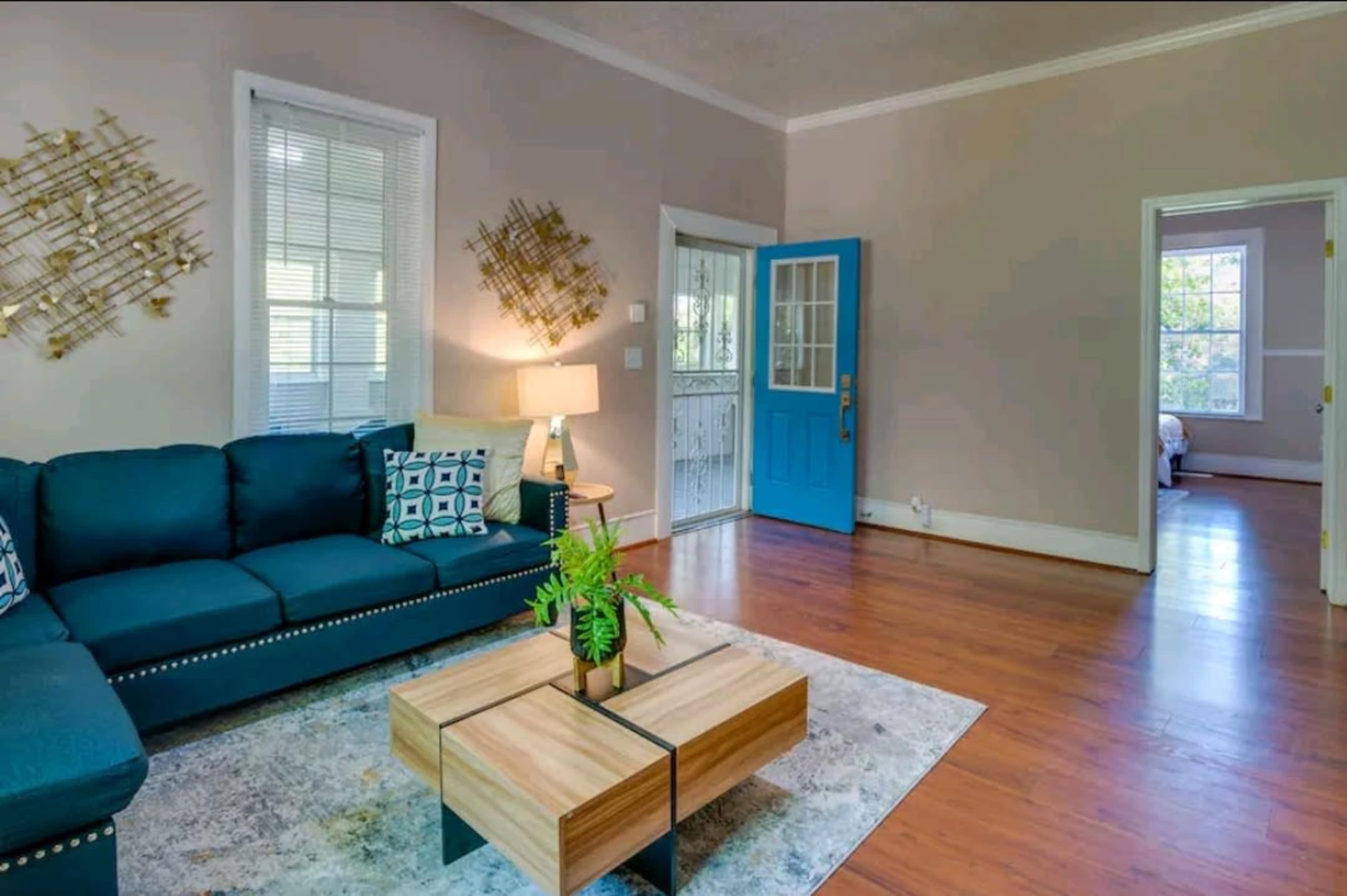 The image shows a living room featuring a blue couch, a coffee table, and a bright blue front door.