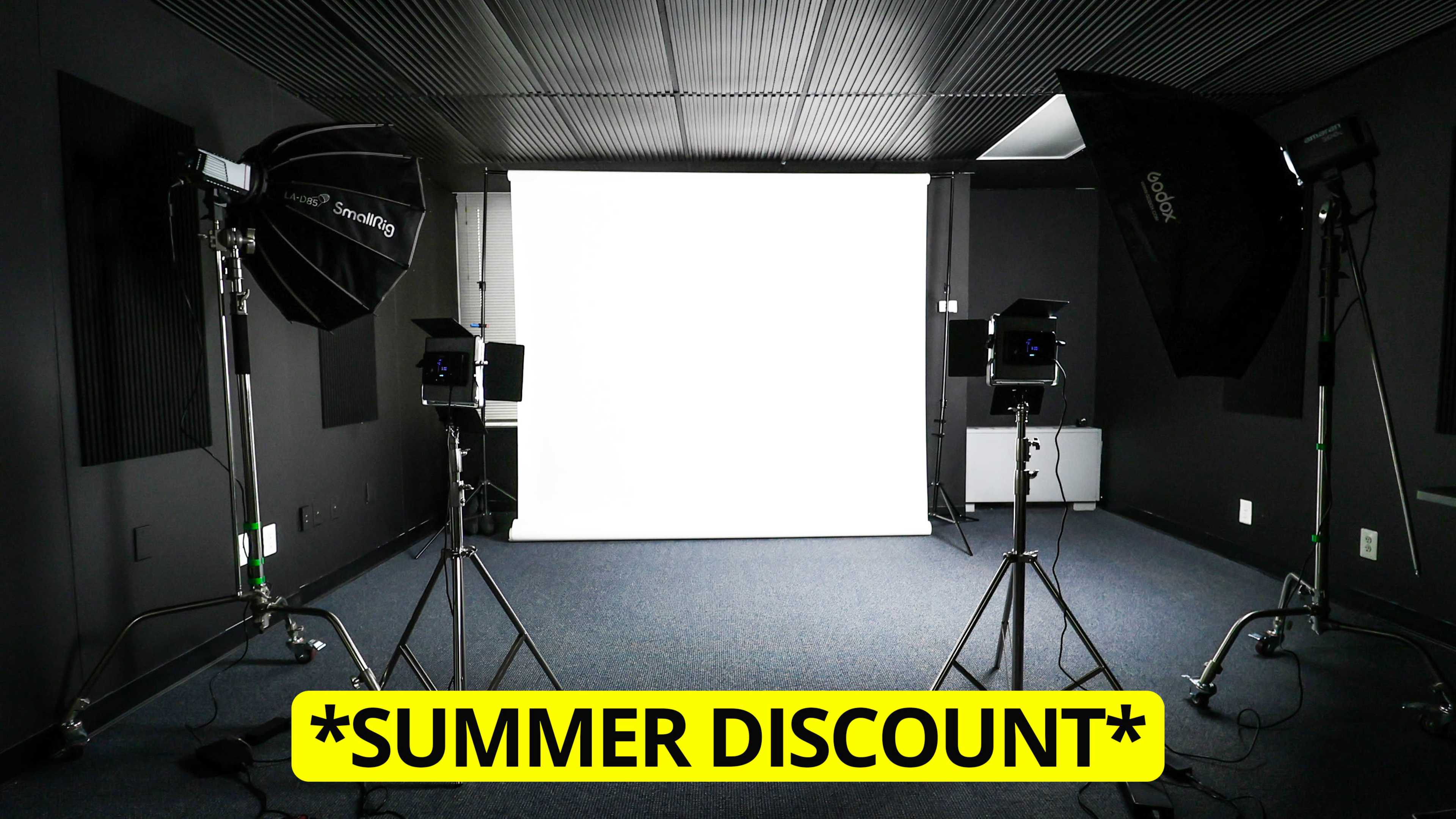 The image shows a photography studio setup with two large softbox lights and a blank white backdrop.