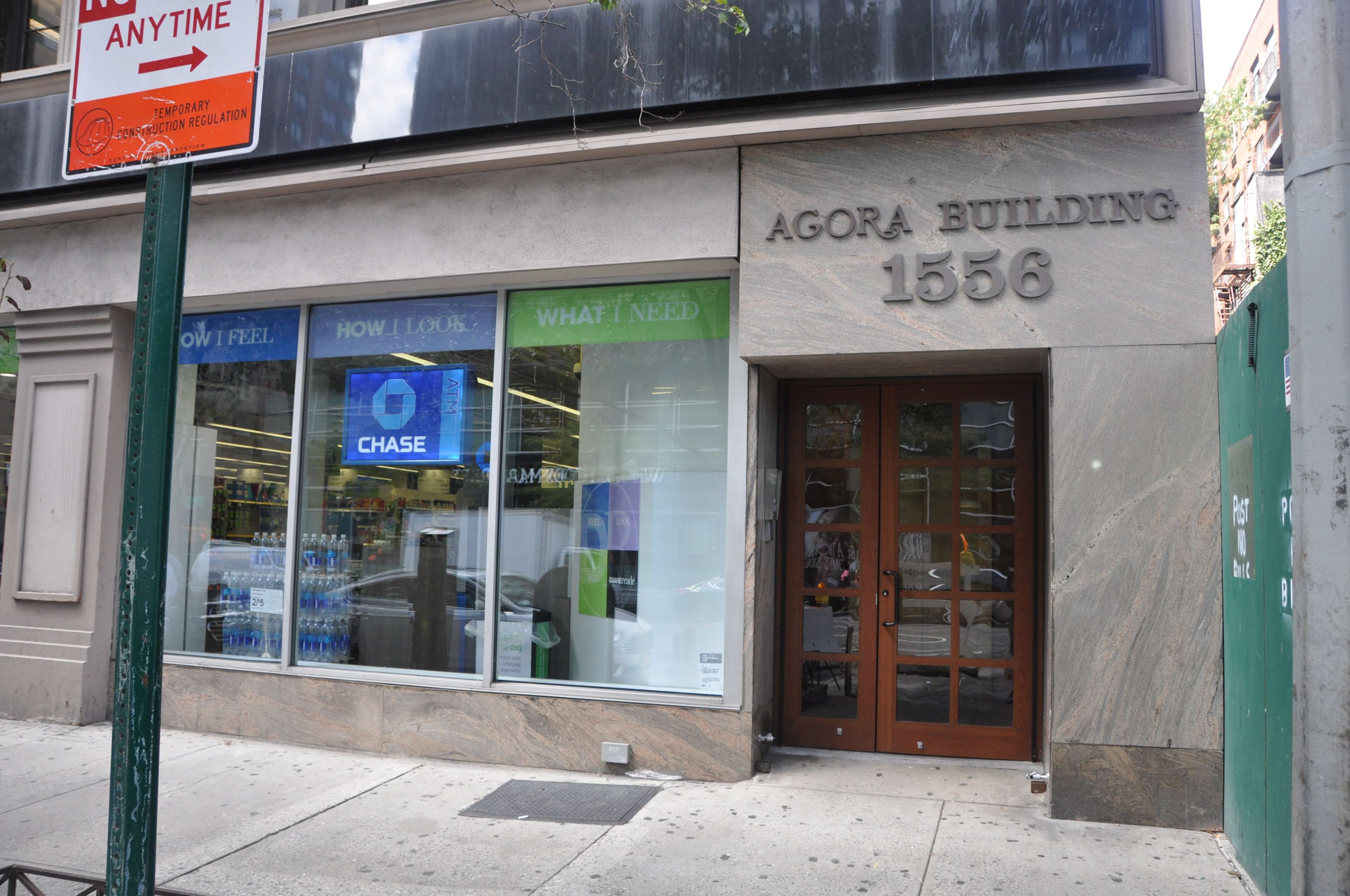 The entrance to the Agora Building at 1556, featuring large windows with signage for Chase Bank and various advertisements.