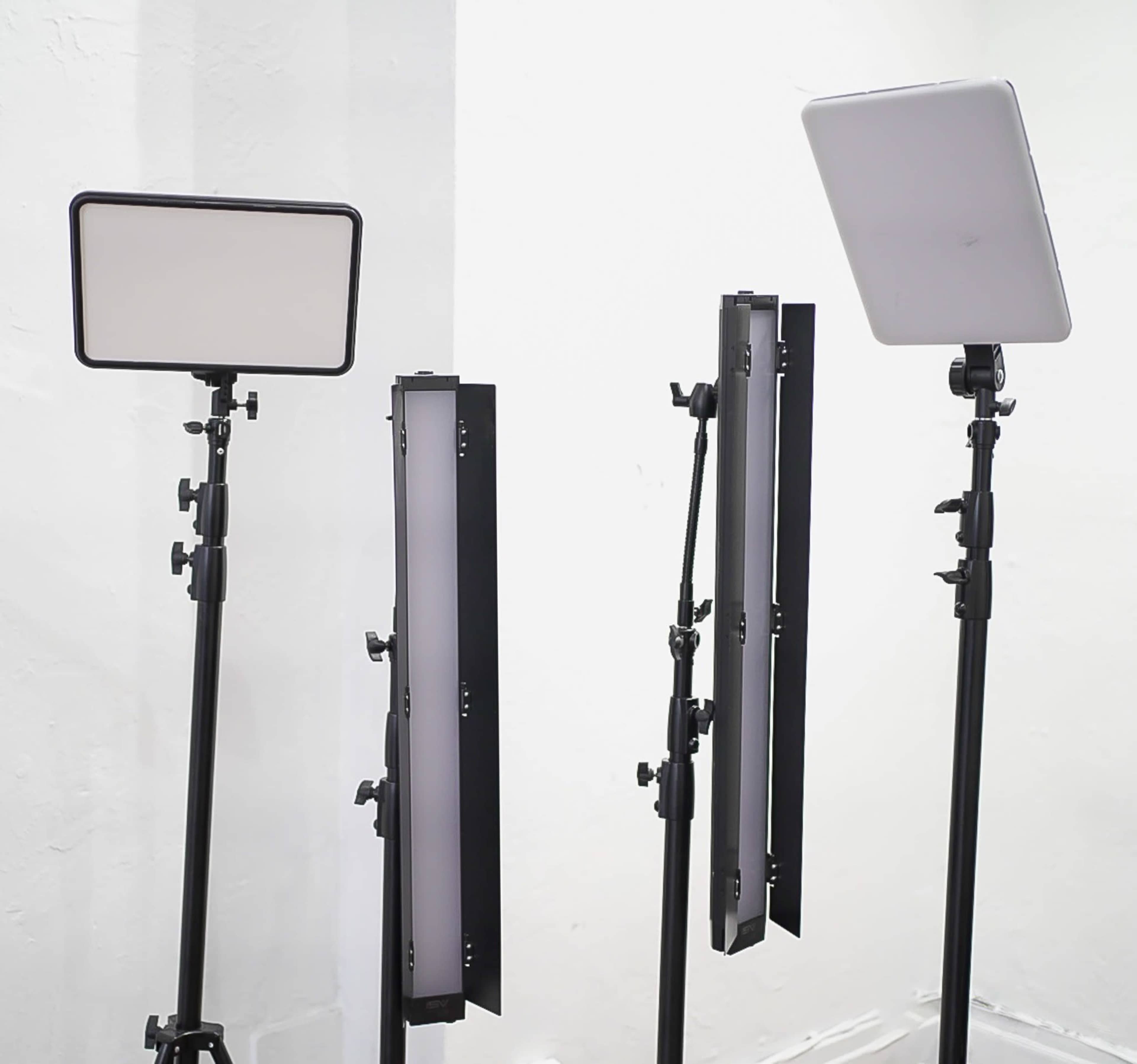 Three lighting fixtures on adjustable stands set against a white wall.