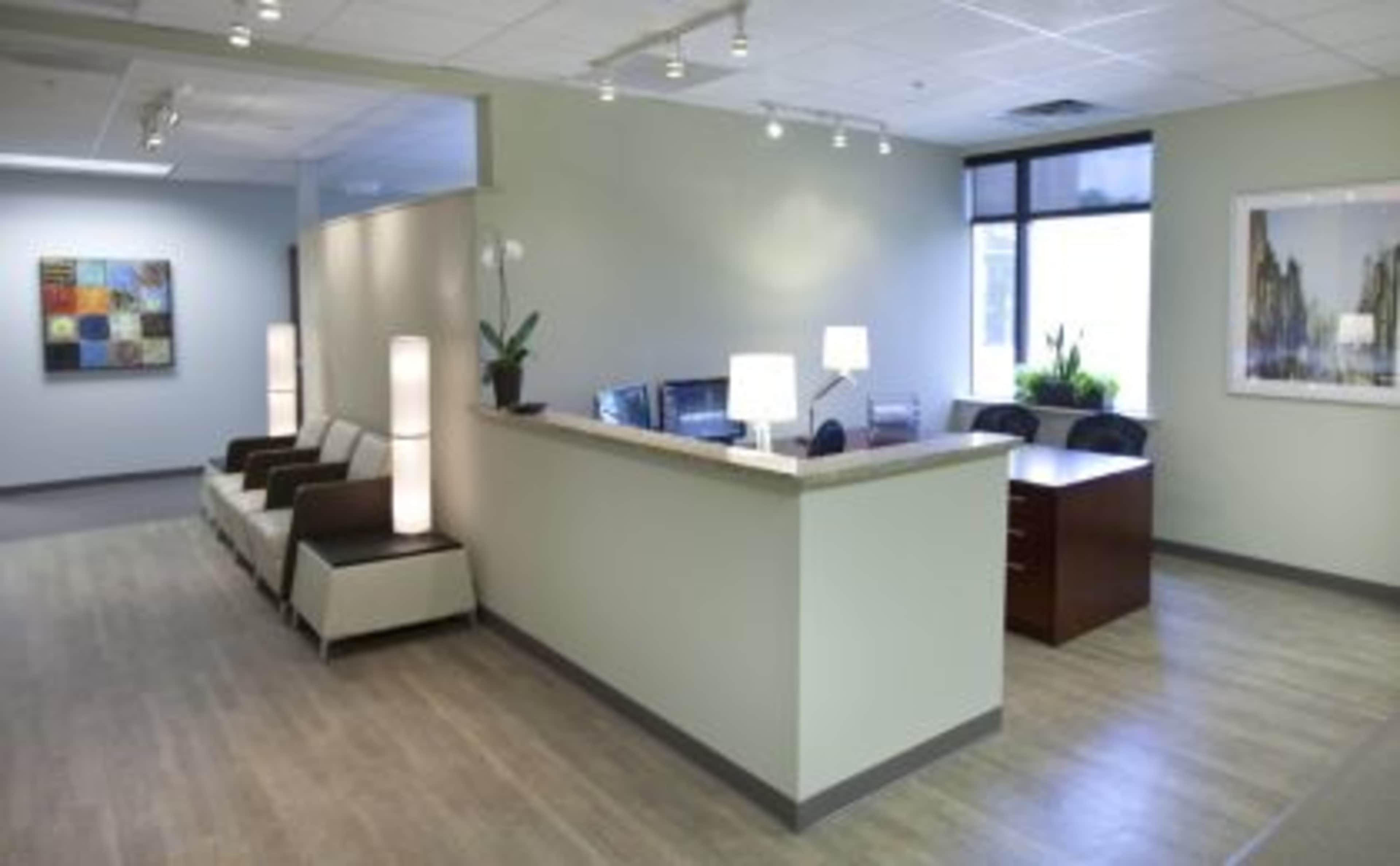 A modern office reception area with seating, a desk, and abstract artwork on the walls.