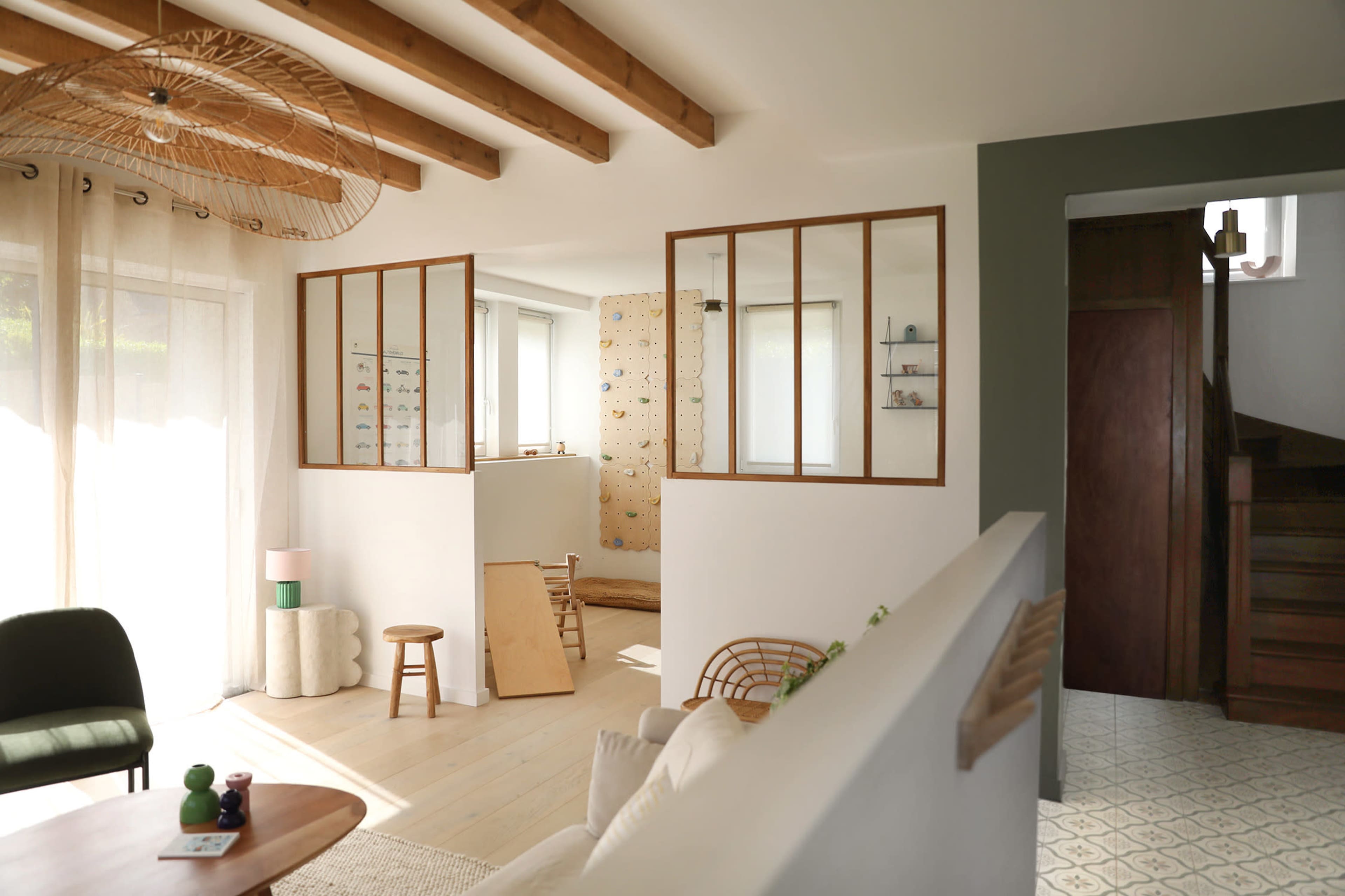 A modern interior features an open layout with wooden beams, a cozy seating area, and a climbing wall in a bright, airy space.