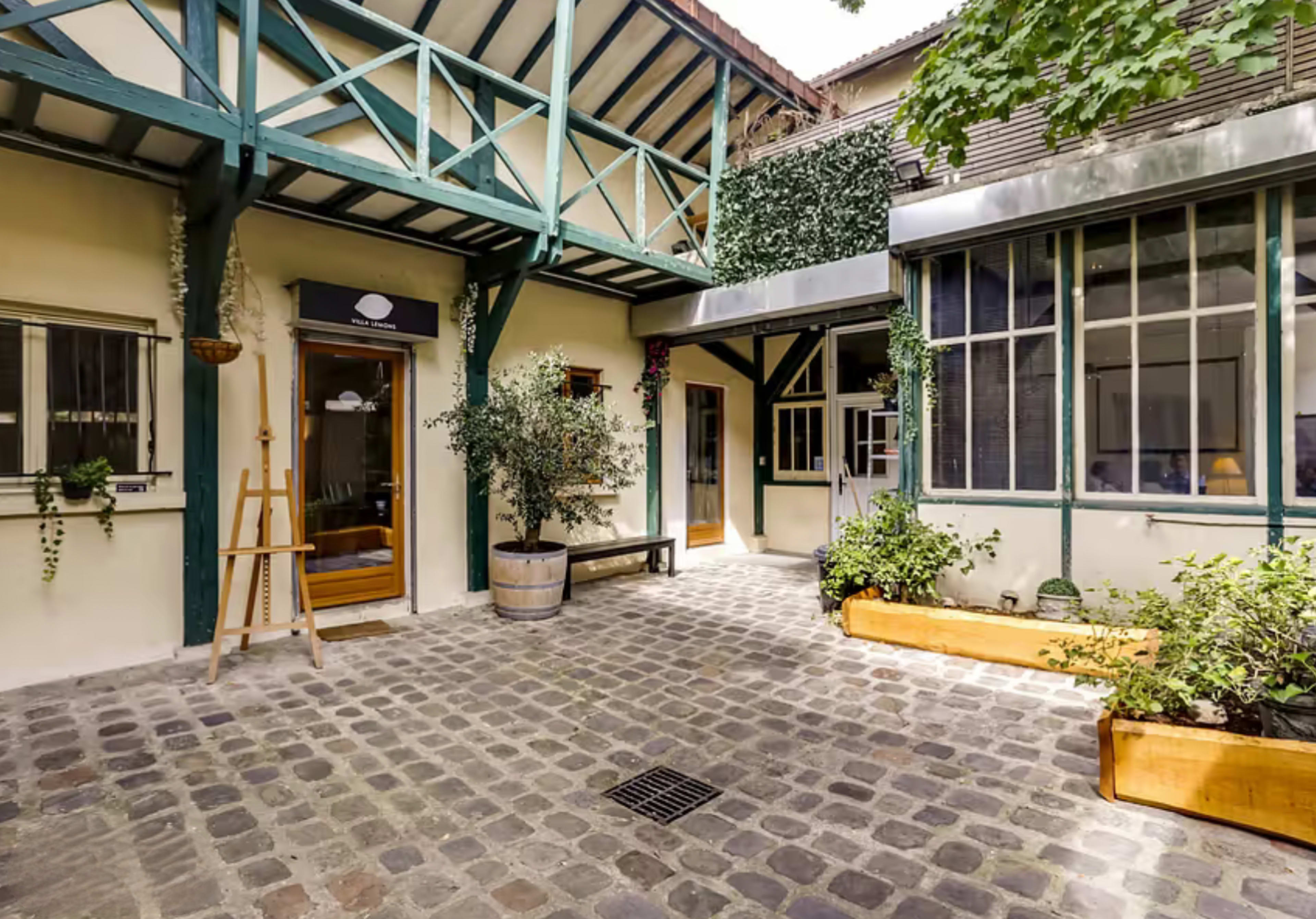 A cobblestone courtyard surrounded by buildings with wooden beams and greenery.