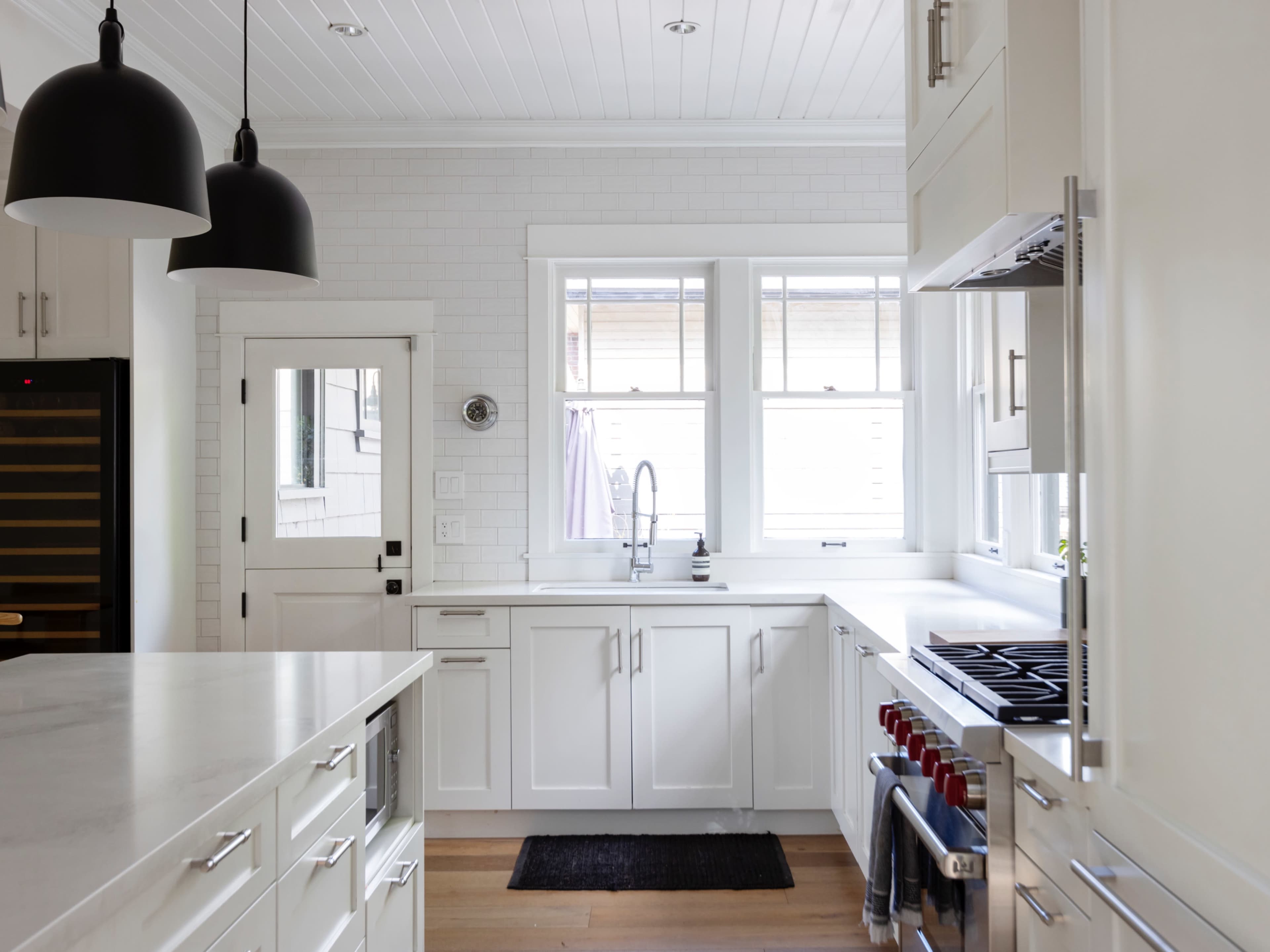 A modern kitchen with white cabinetry, a large countertop, and stainless steel appliances, featuring a window that provides natural light.