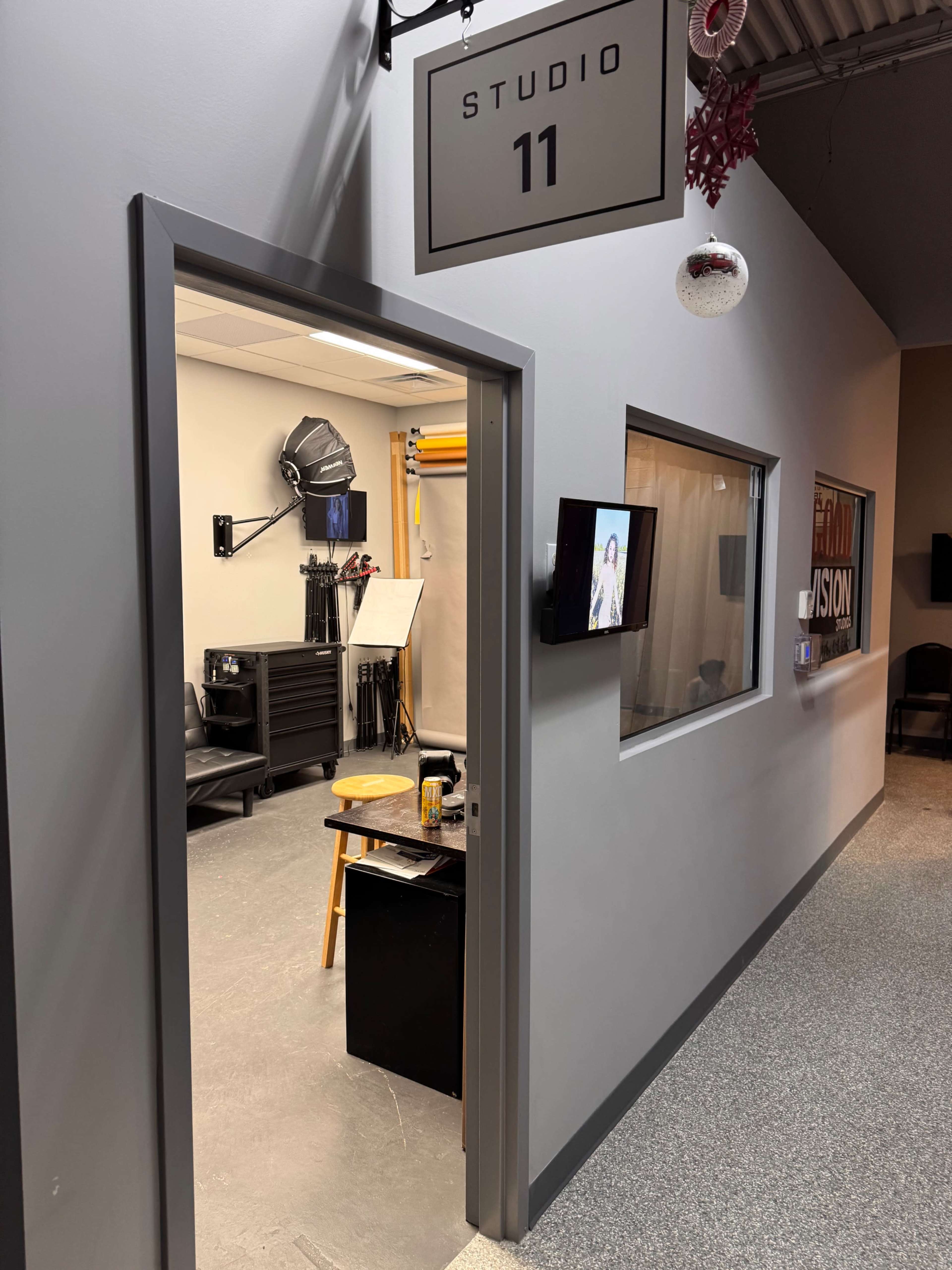 The image shows an entrance to a studio labeled "STUDIO 11," with a glimpse of equipment and a chair visible inside.