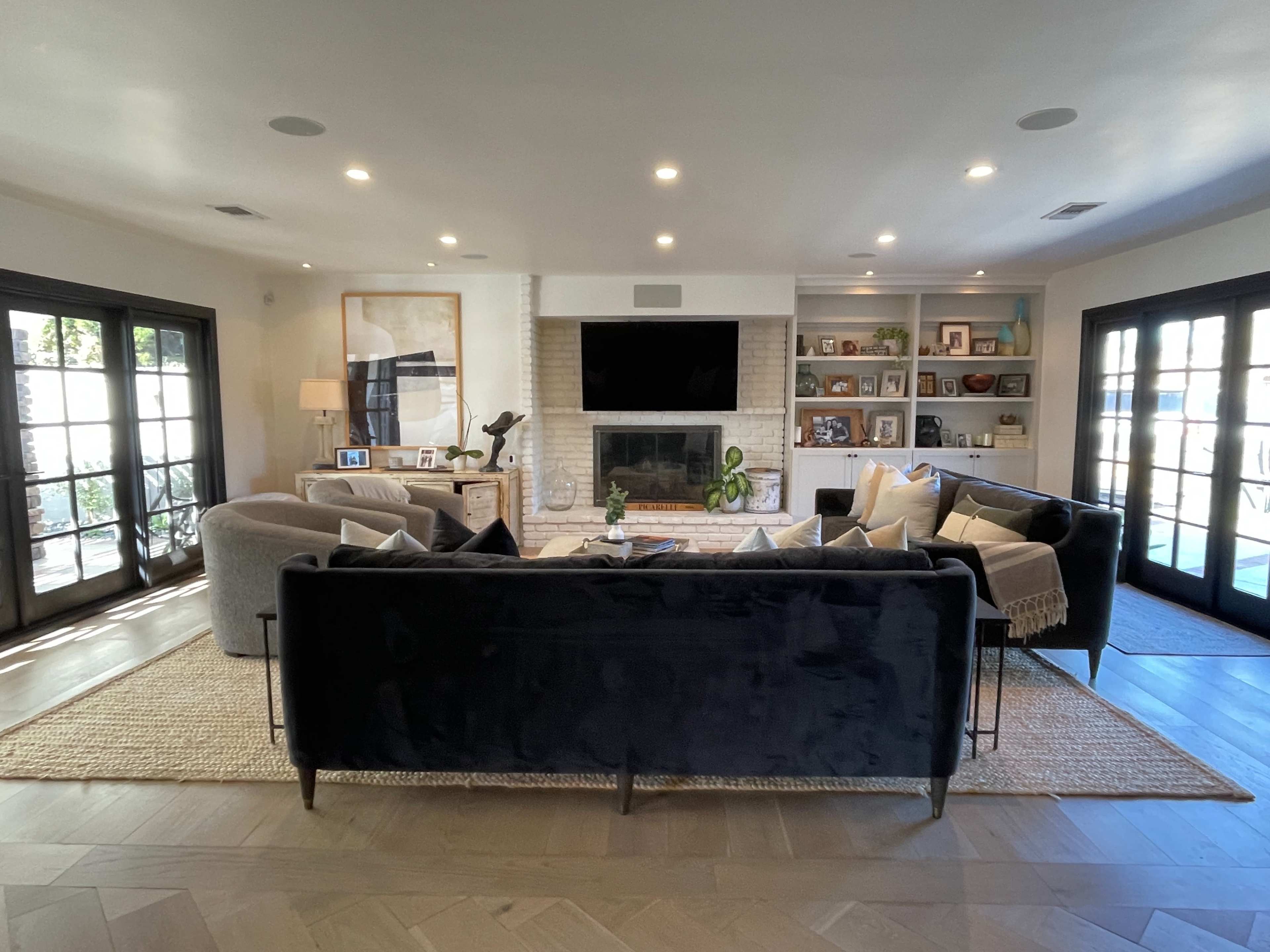 A modern living room features a fireplace, a large television, and comfortable seating arranged around a central area rug.