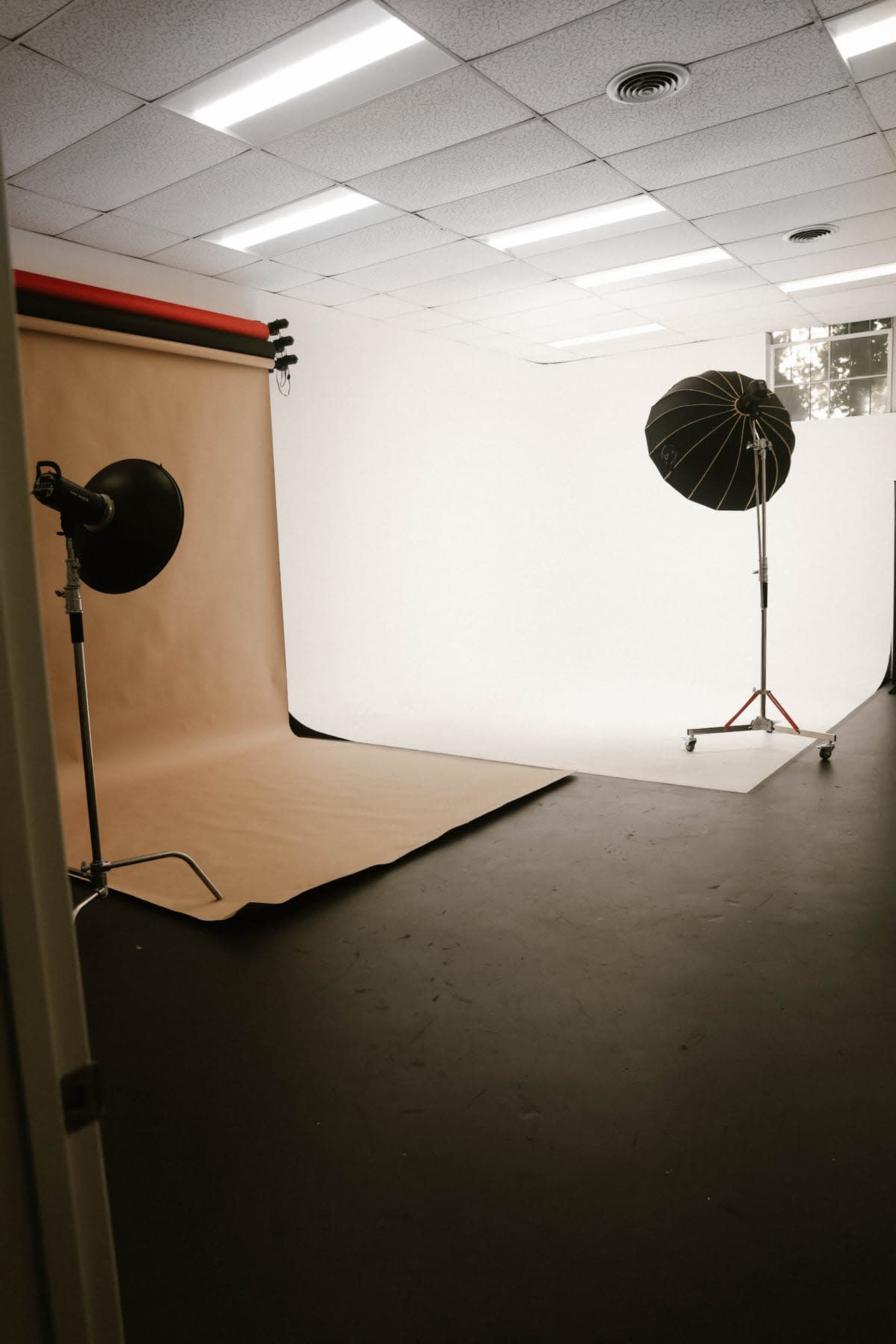 A photography studio with a brown backdrop, a white backdrop, and two lighting setups.