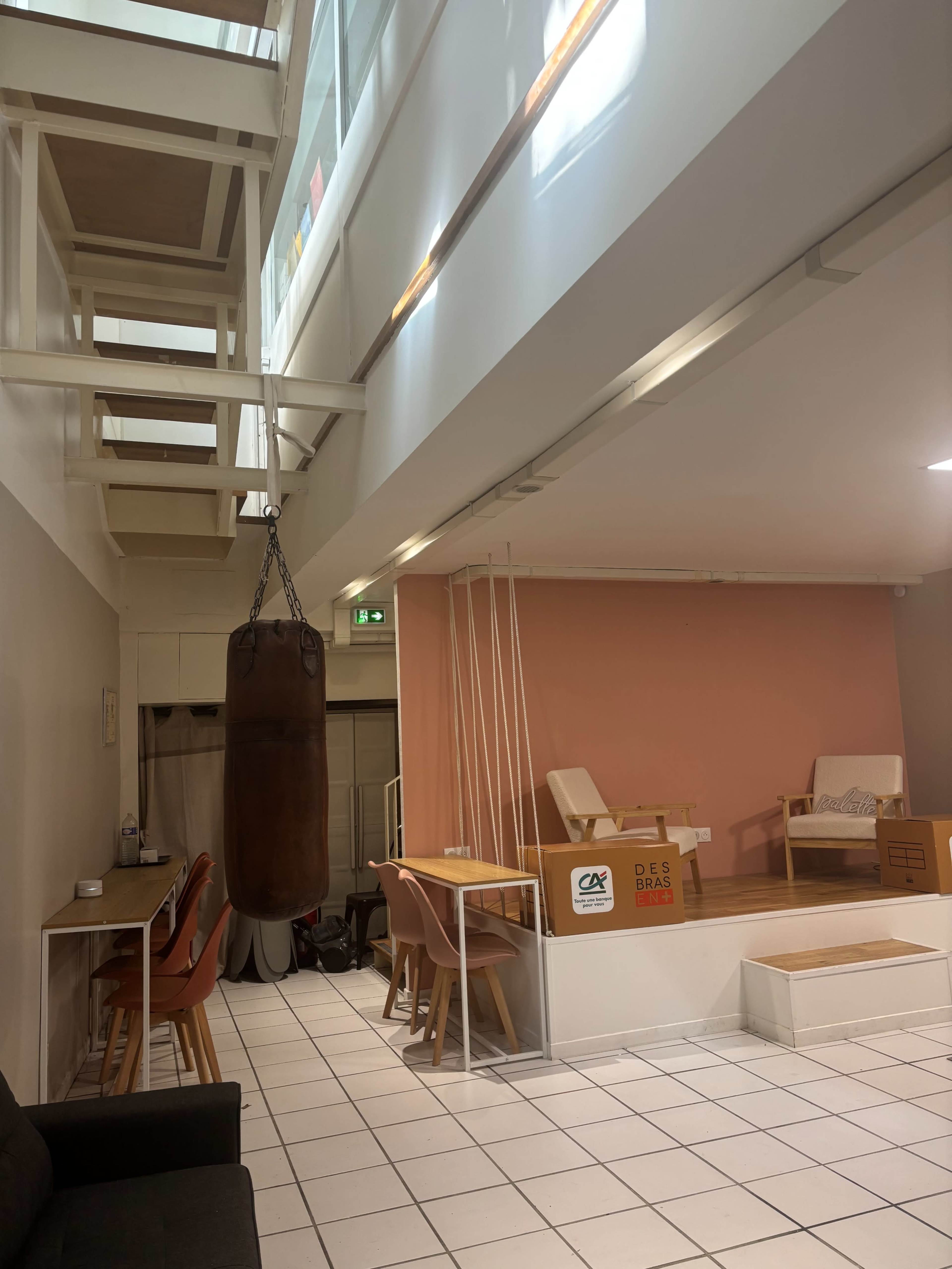 The image shows a modern, open space featuring a decorative boxing bag, multiple seating areas, and a split-level design with wooden accents.