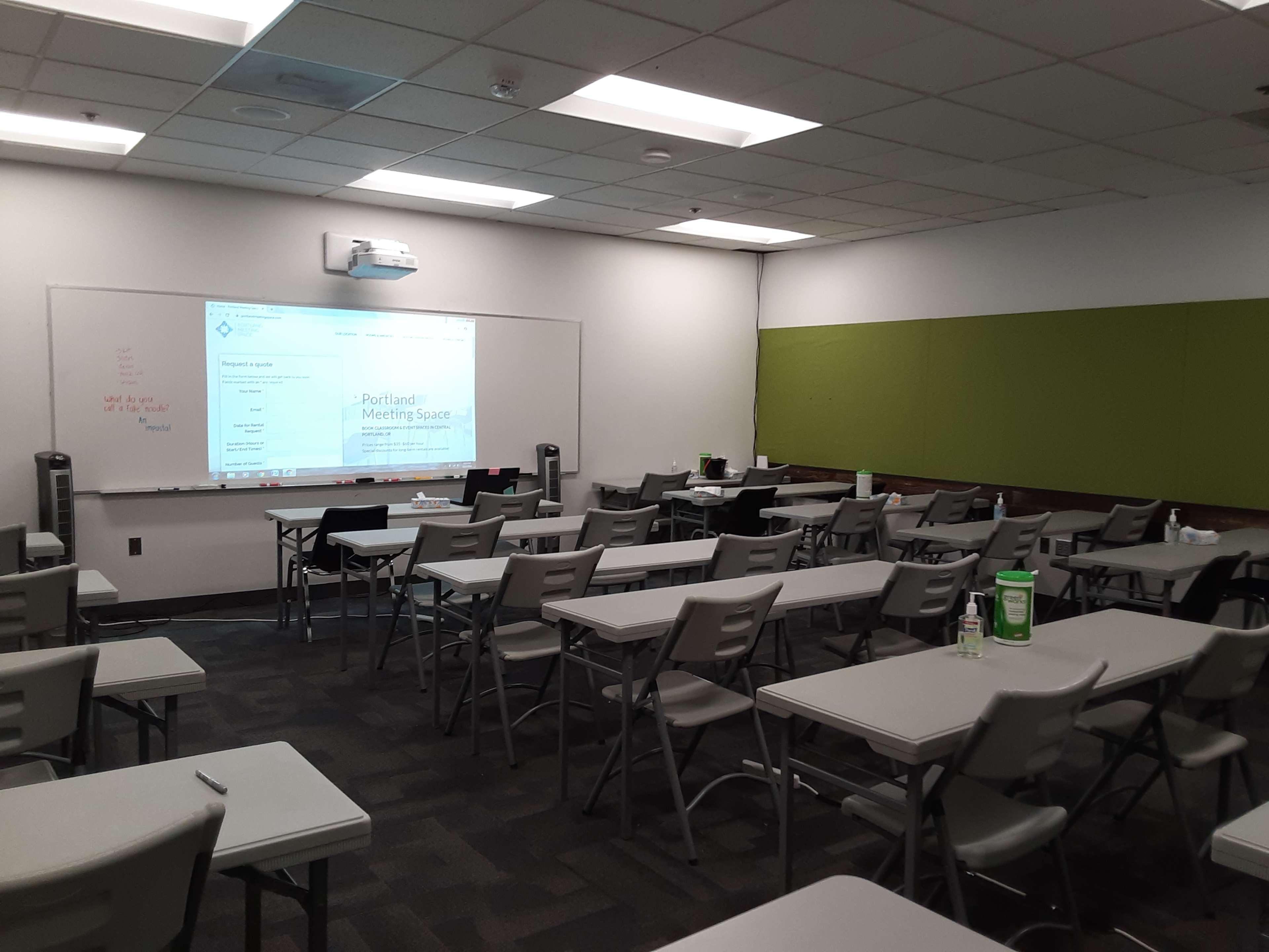 A classroom setting with arranged desks and a presentation screen at the front.