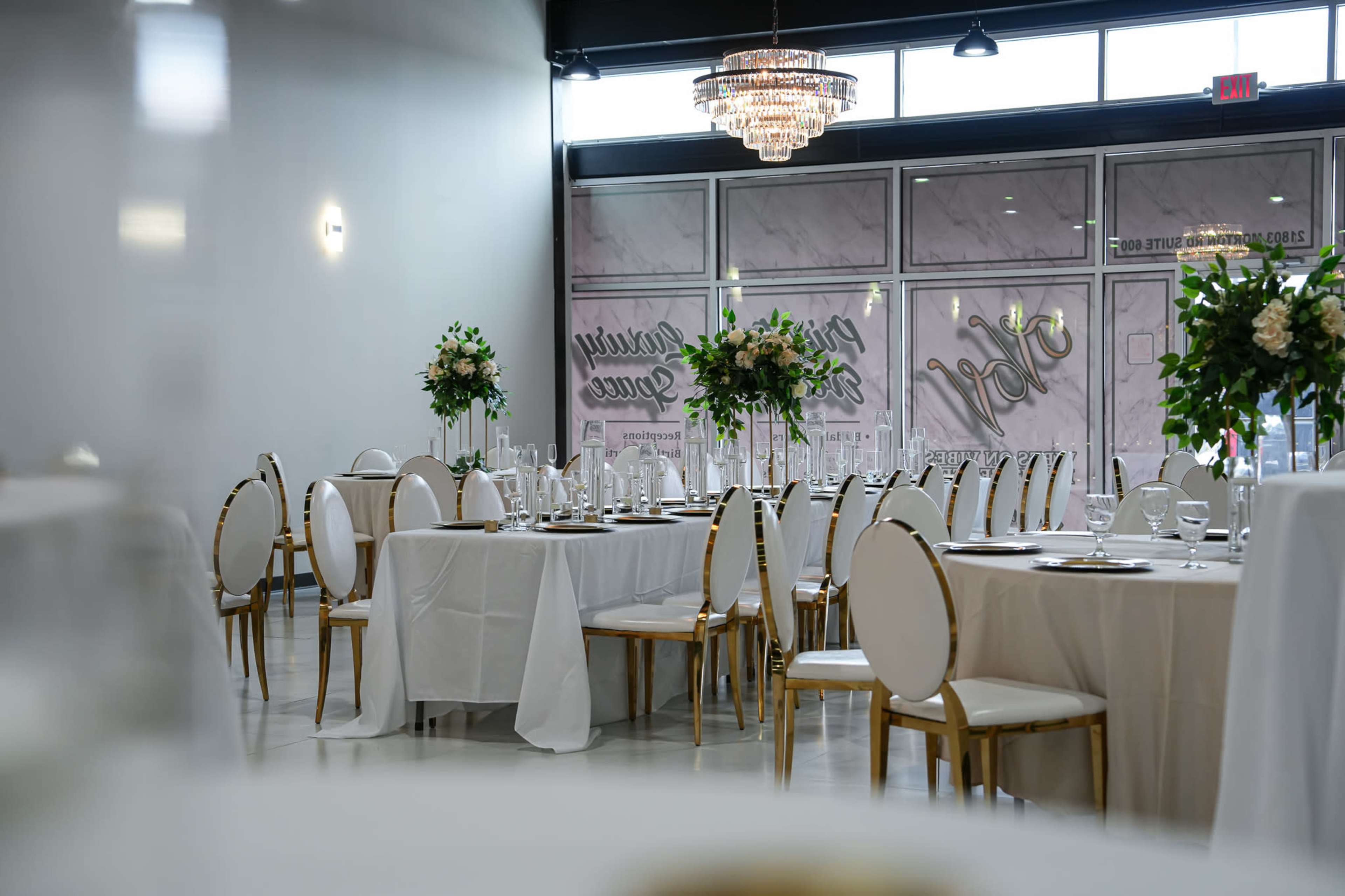 A banquet-style dining area with round tables set for an event, featuring white tablecloths and elegant floral centerpieces.