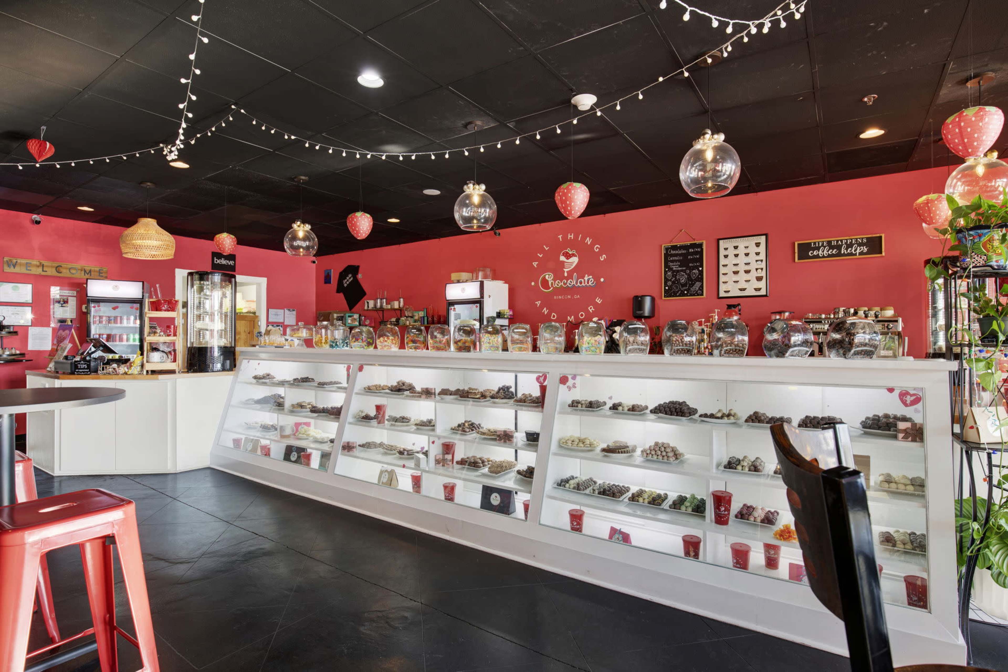 The image shows a colorful candy shop featuring a bright pink interior with display cases filled with various sweets and treats.