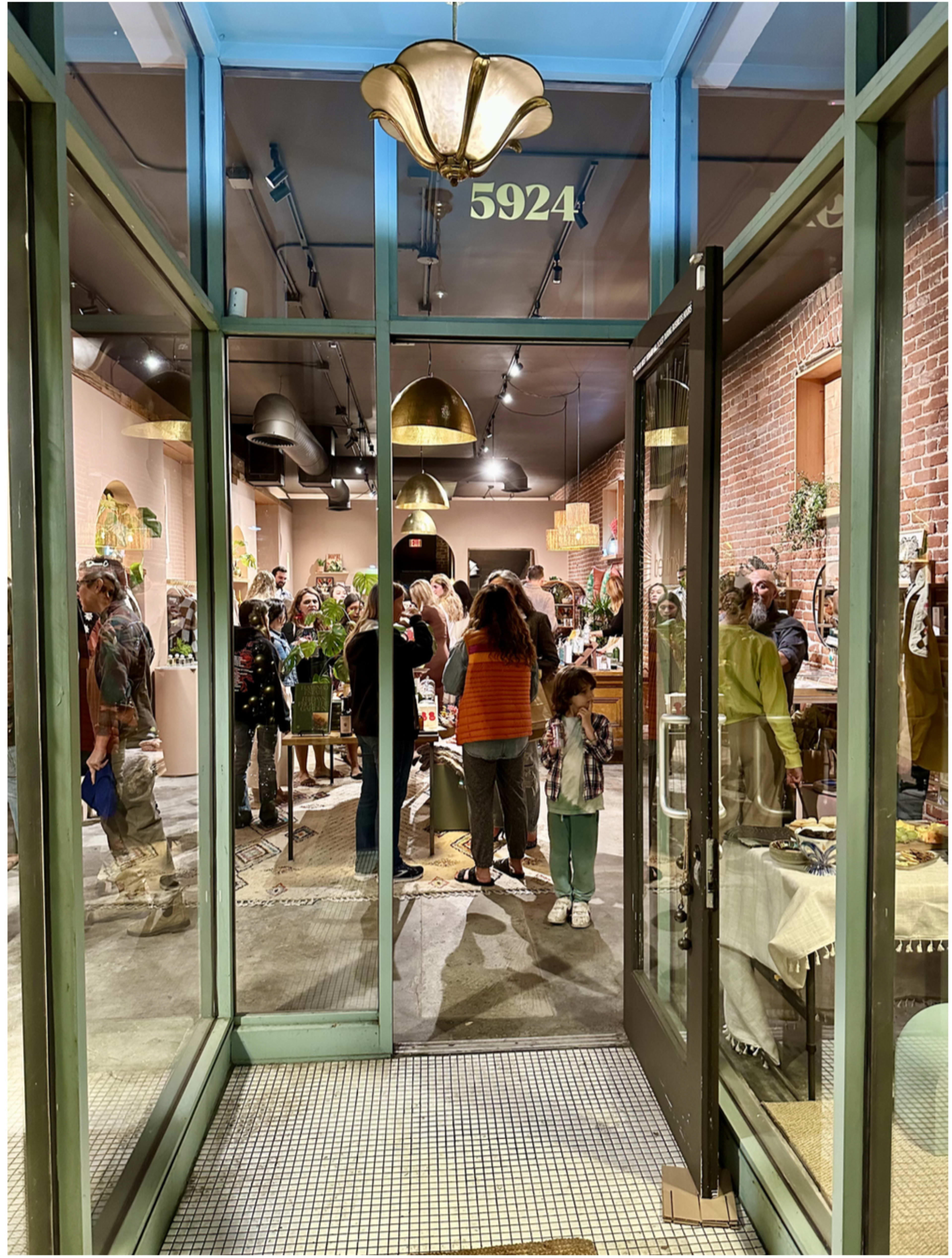 A crowded retail store is seen from the entrance, showcasing people interacting and browsing various products inside.