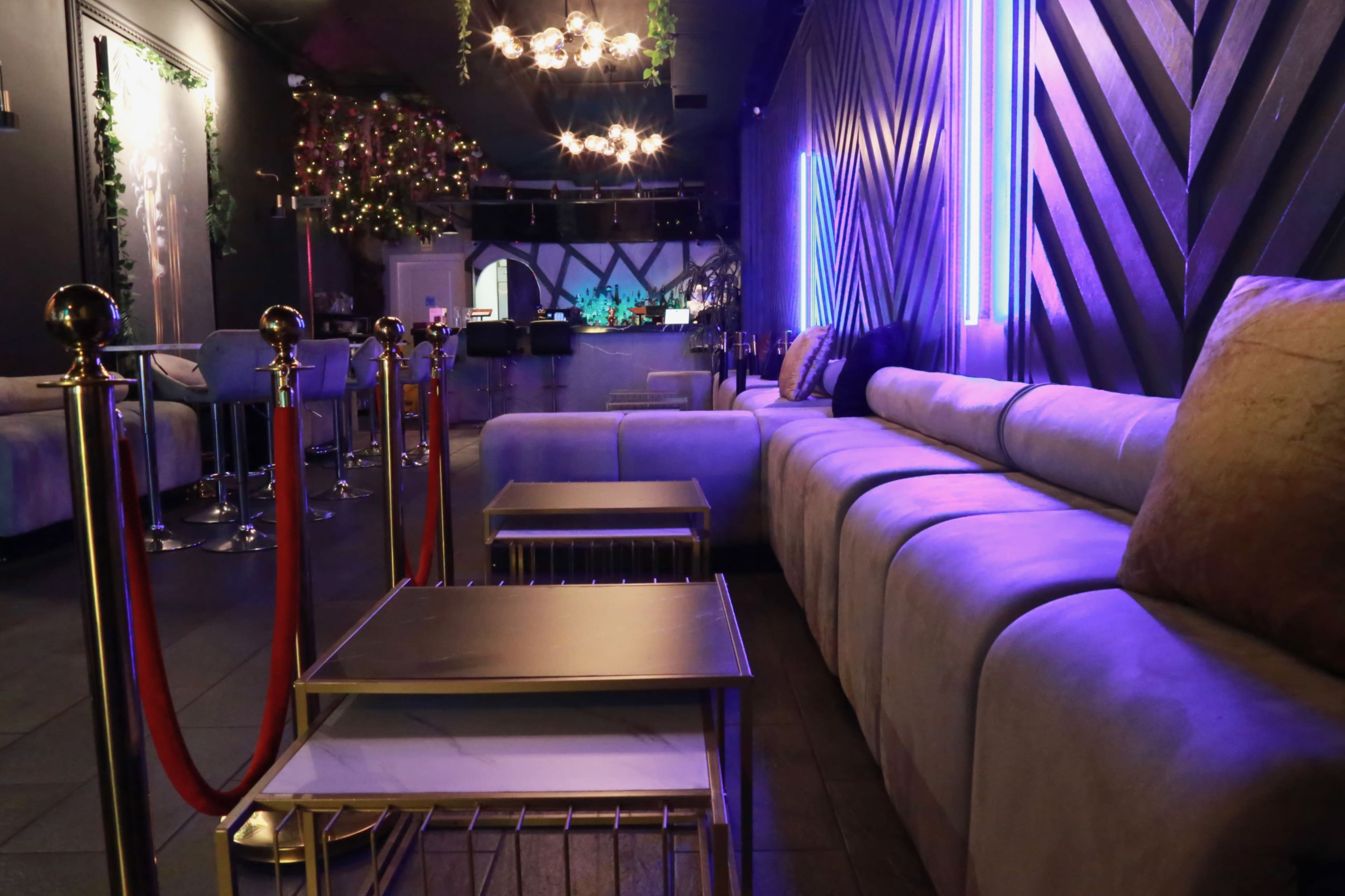 A modern lounge area with a curved, plush sofa and metallic tables under ambient lighting.